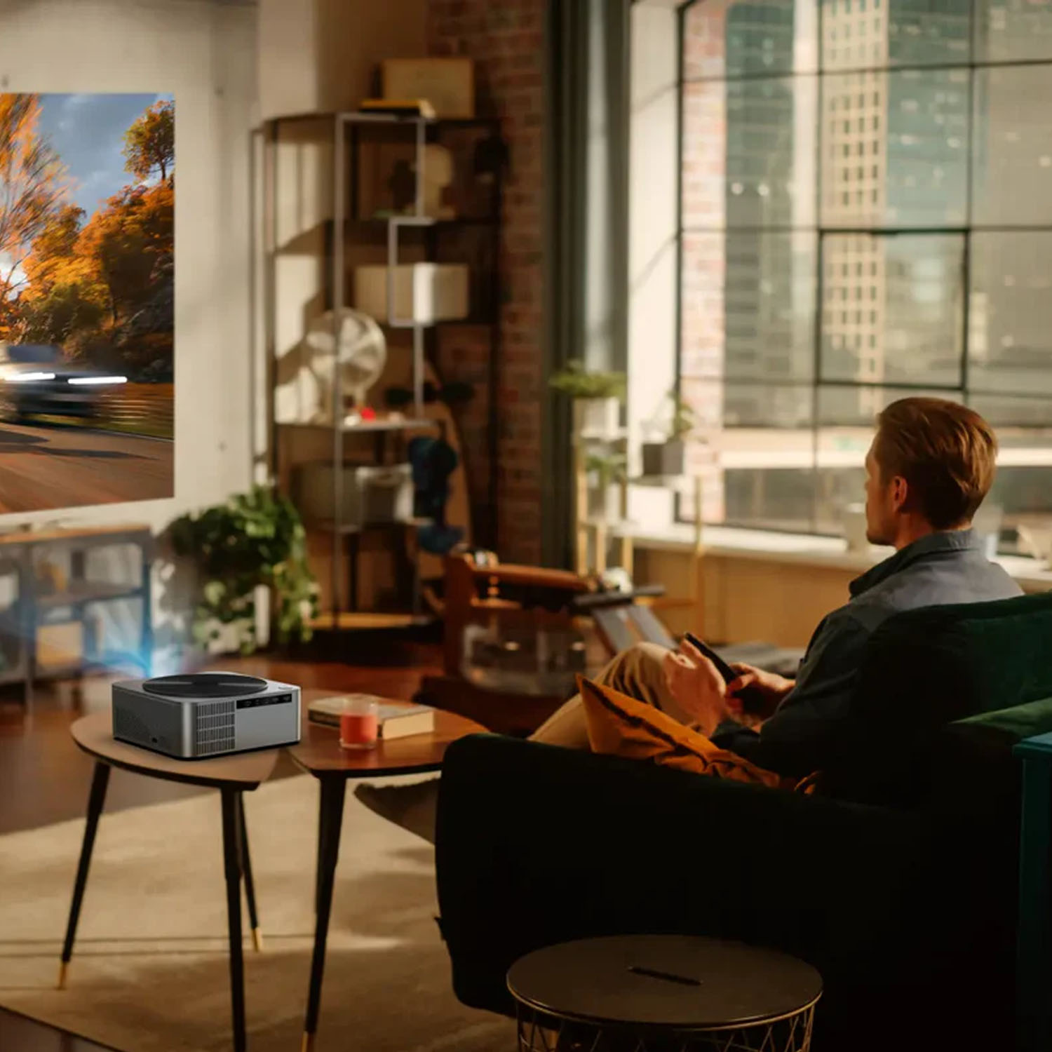 Mężczyzna ogląda film wyświetlany na ścianie, używając projektora na stole.