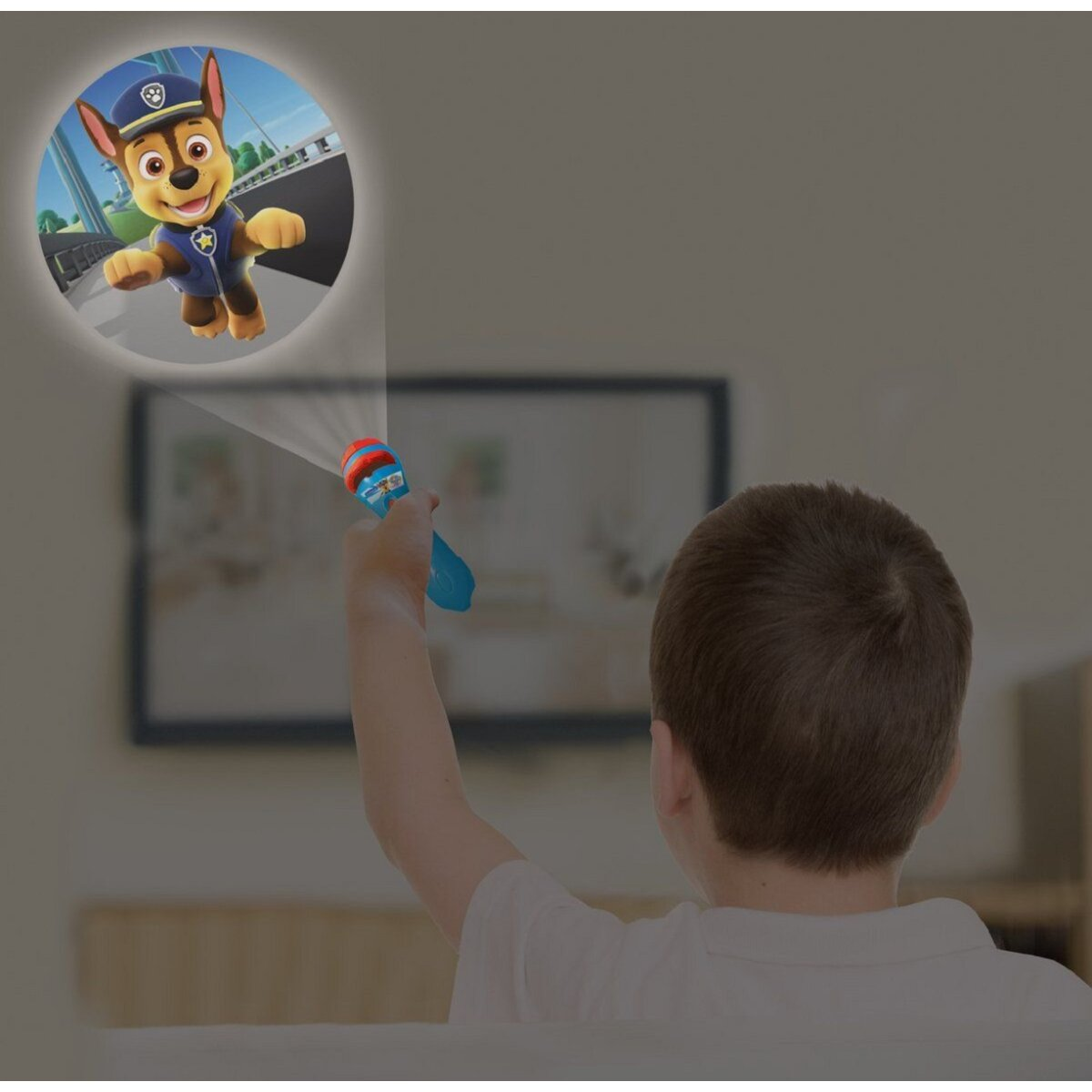 Chłopiec celuje projektorem Paw Patrol. Ciemne tło.