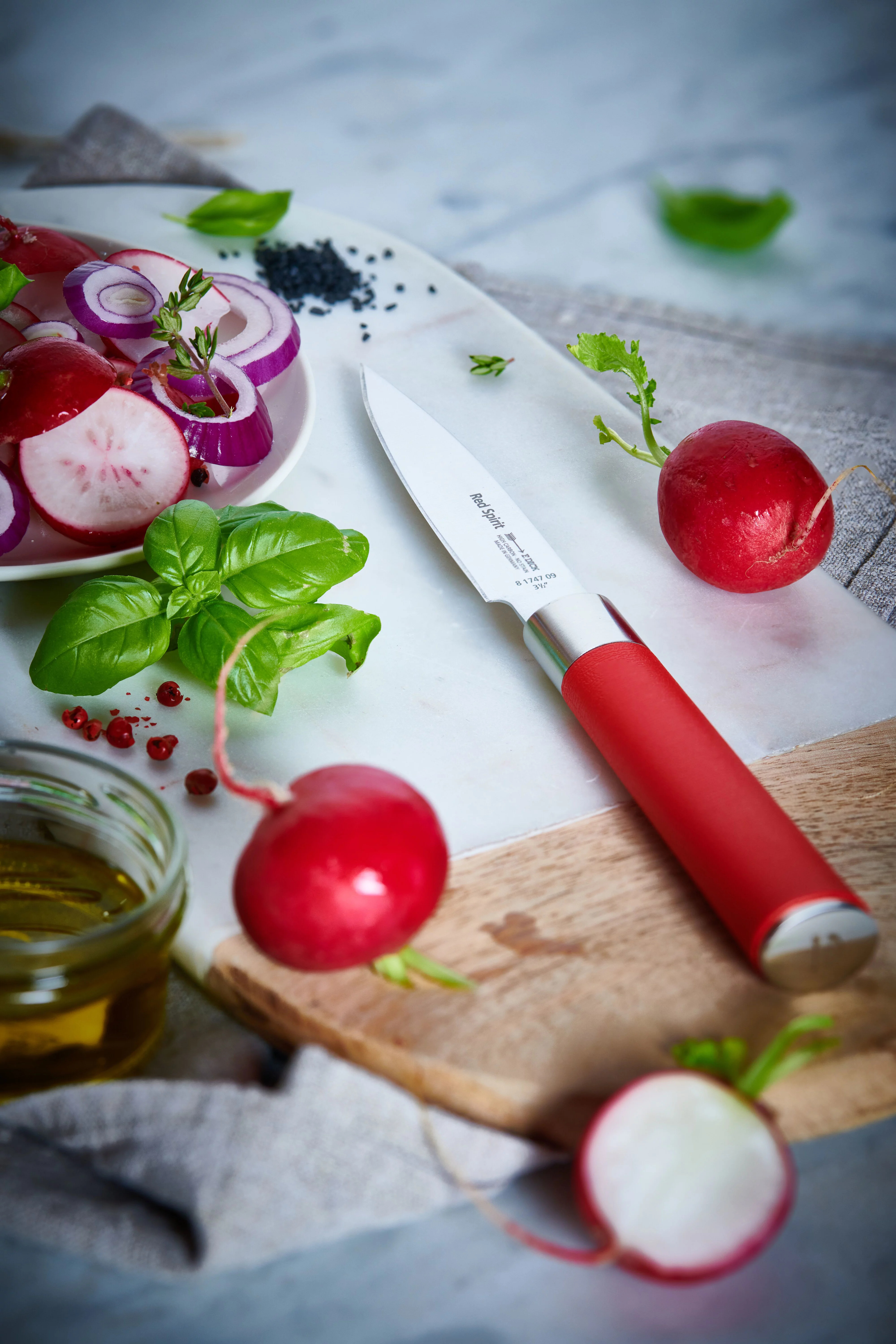 Nóż z czerwonym uchwytem kroi rzodkiewkę na desce do krojenia.