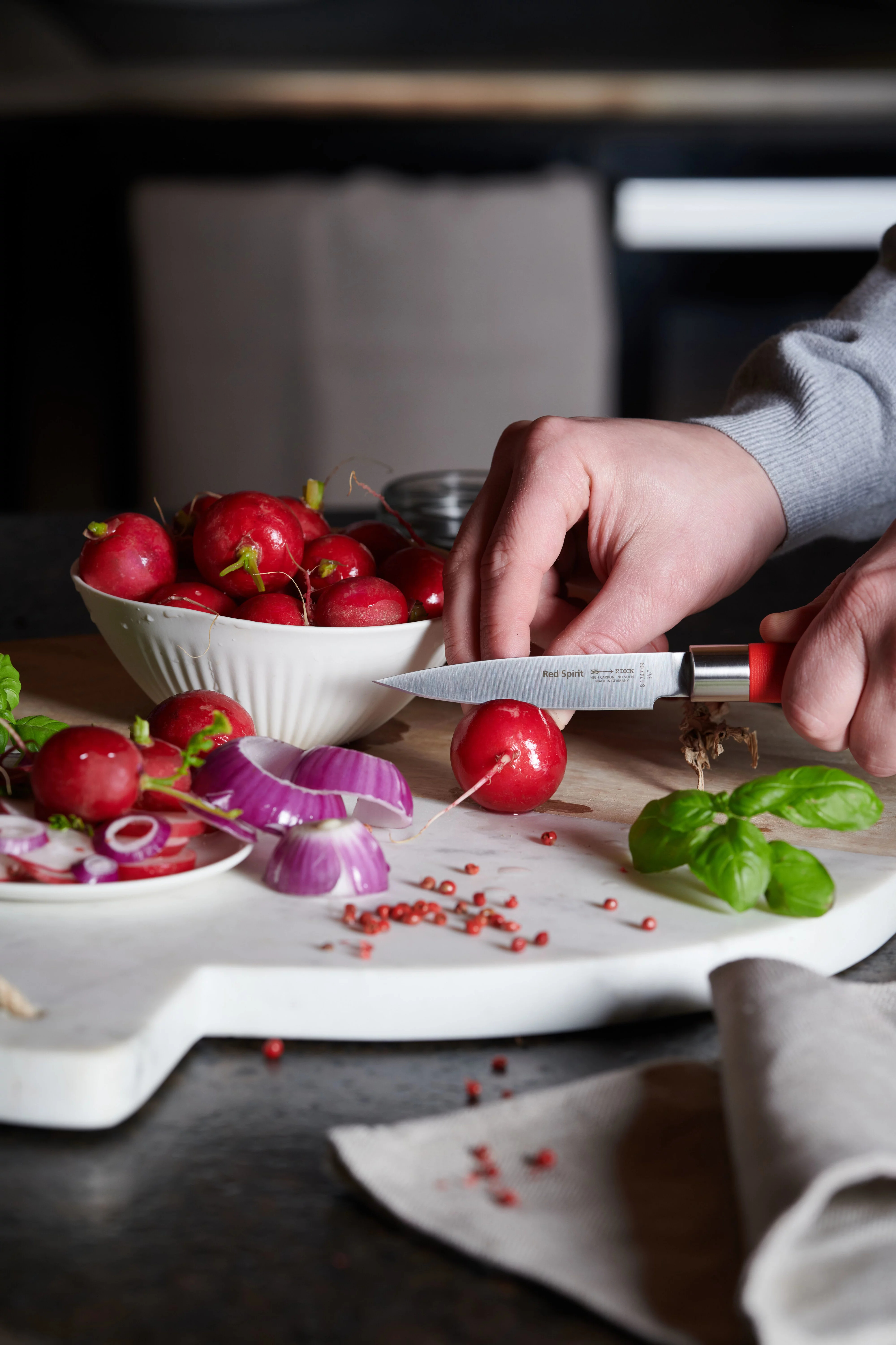 Nóż z czerwonym uchwytem kroi rzodkiewkę.