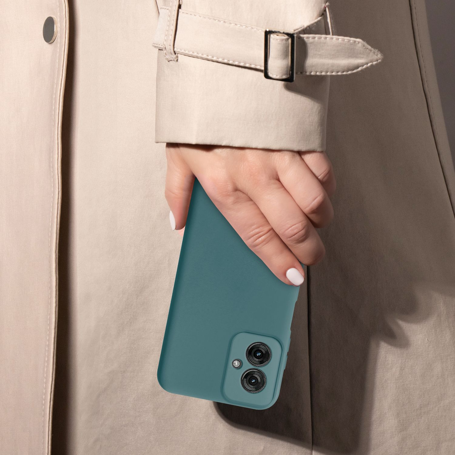 Eine Hand, die ein türkisfarbenes Telefon in einem beigefarbenen Trenchcoat hält. Die Kamera des Telefons ist sichtbar.
