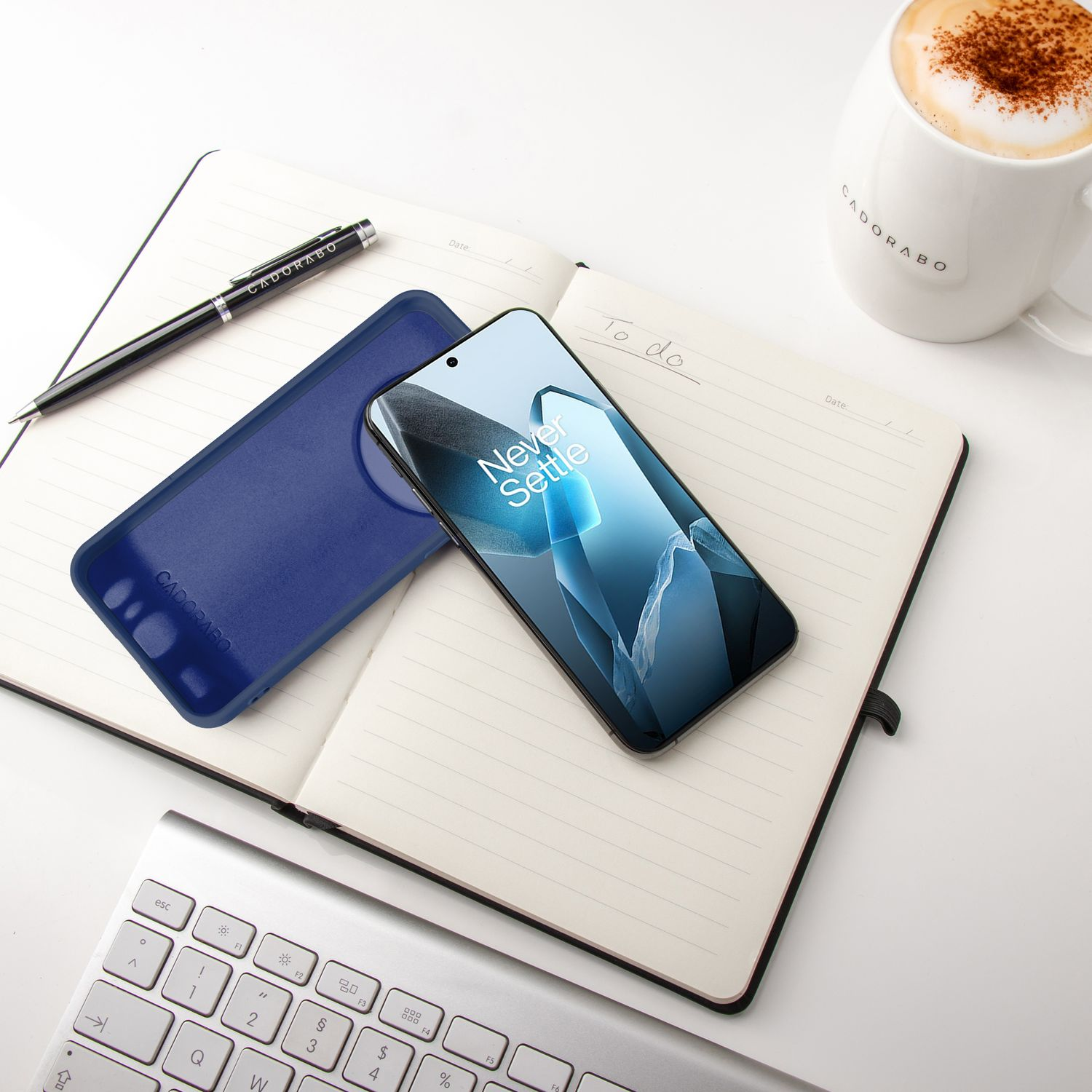 Telefon mit Bildschirm auf Notizblock und blaue Handyhülle. Stift und Kaffeetasse vorhanden.