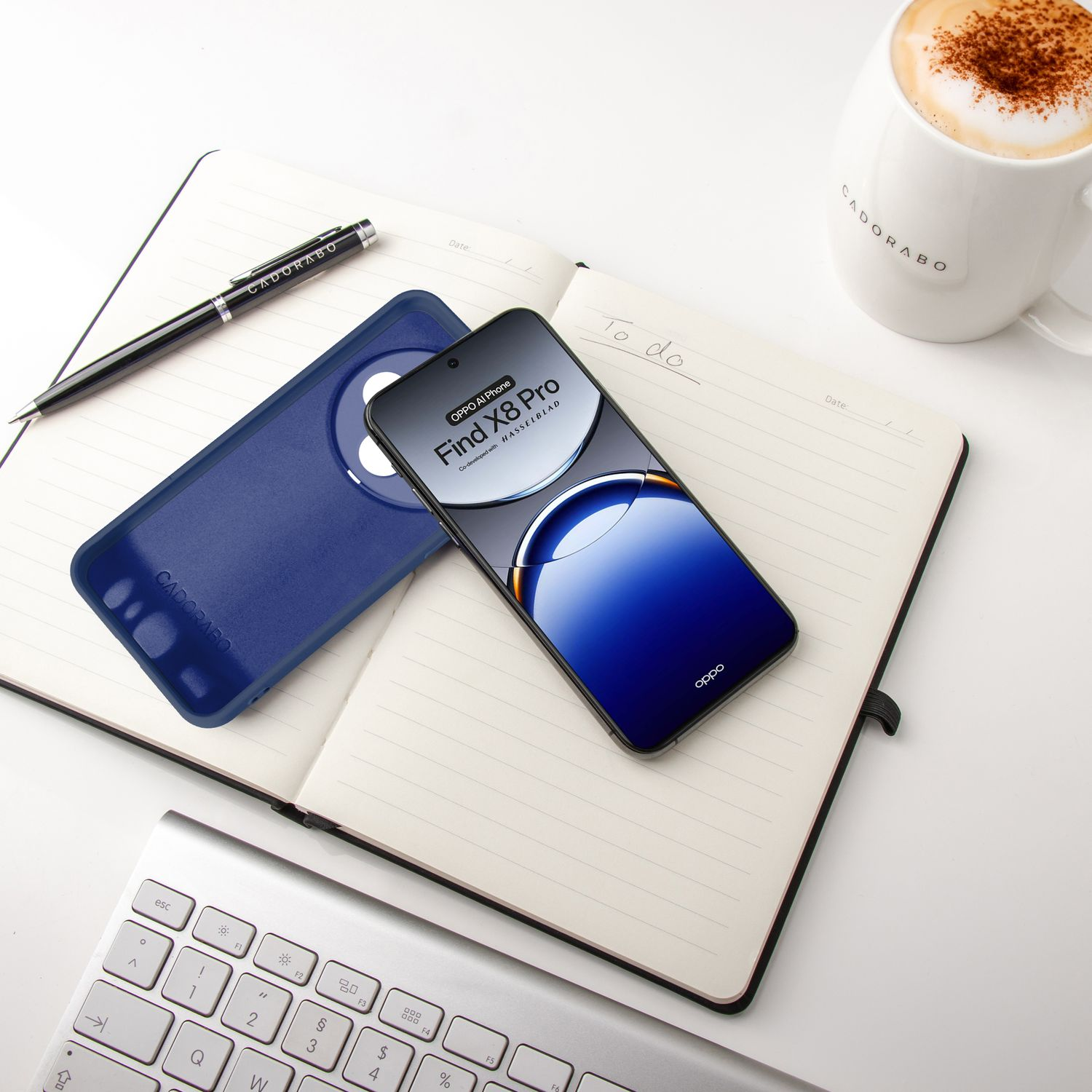 Telefon, Hülle, Stift und Kaffeetasse auf einem Notizblock, weiße Oberfläche.