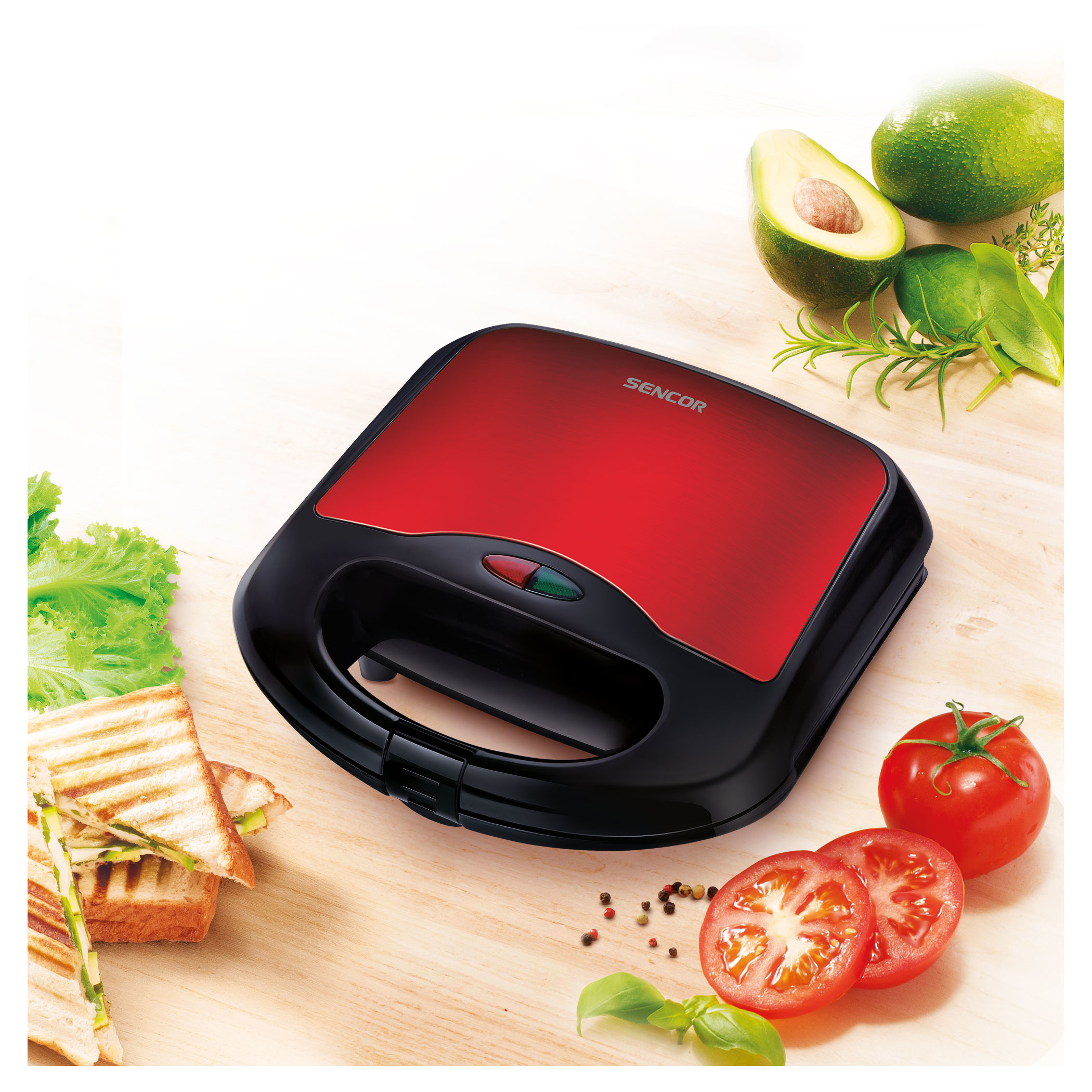 Sandwich maker rosso e nero con sandwich e ingredienti su superficie in legno.
