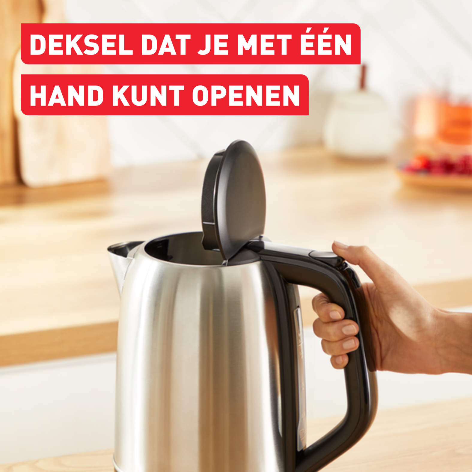 Silberner Wasserkocher. Schwarzer Griff. Hand öffnet Deckel. Text oben in Rot.