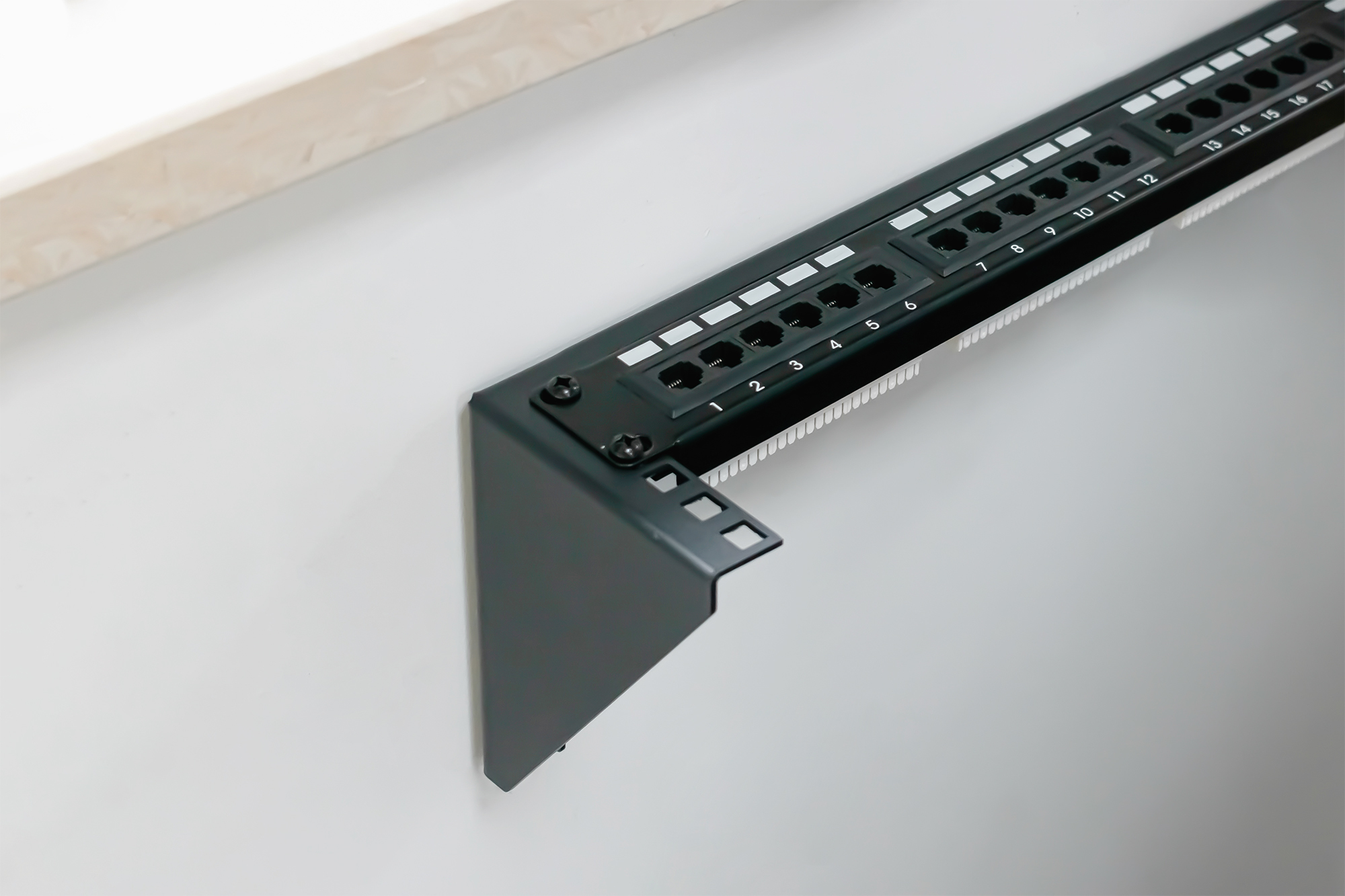 Czarny panel krosowy z ponumerowanymi portami, zamontowany na białej ścianie.