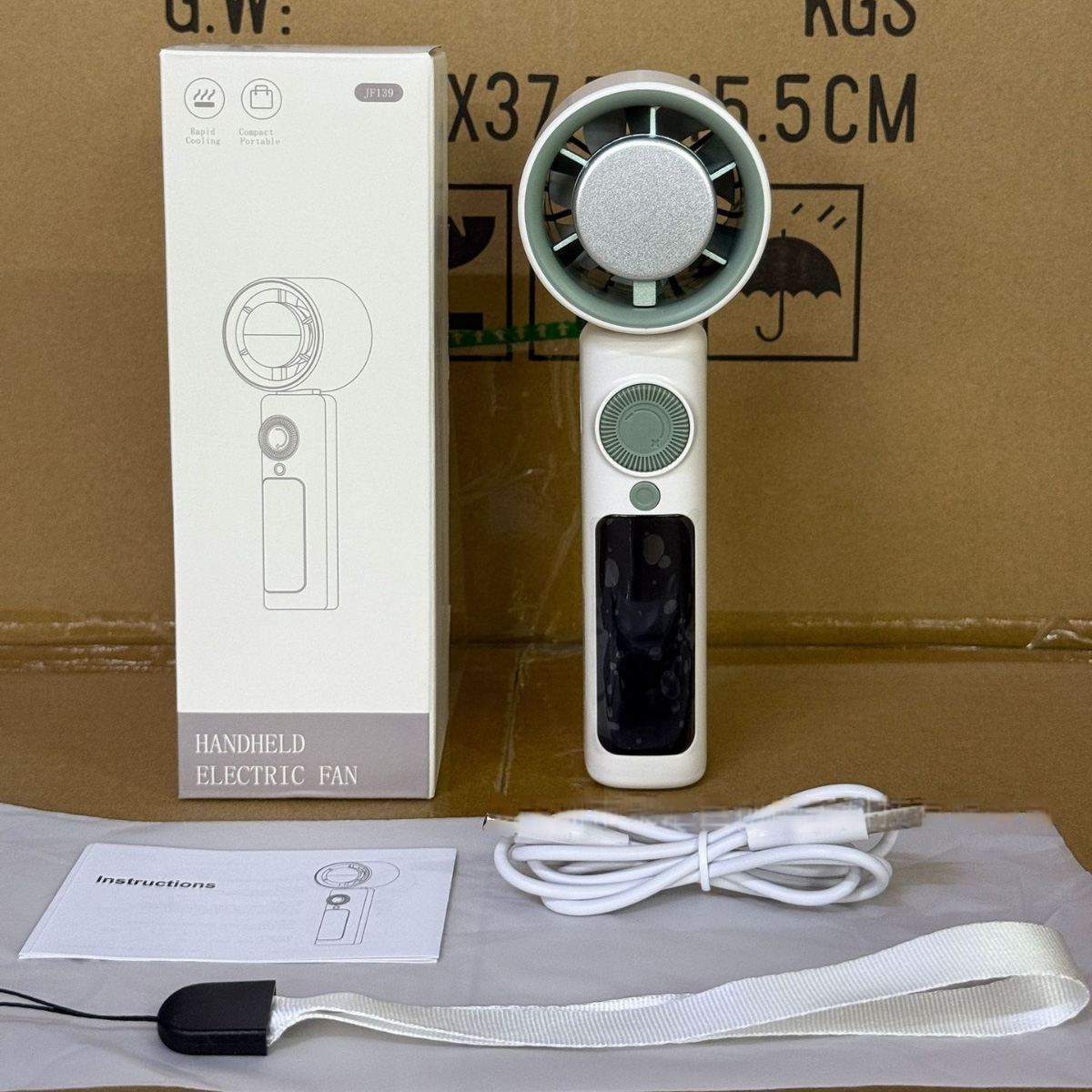 Weißer tragbarer elektrischer Ventilator mit Verpackung, Anleitung, USB-Kabel und Gurt.