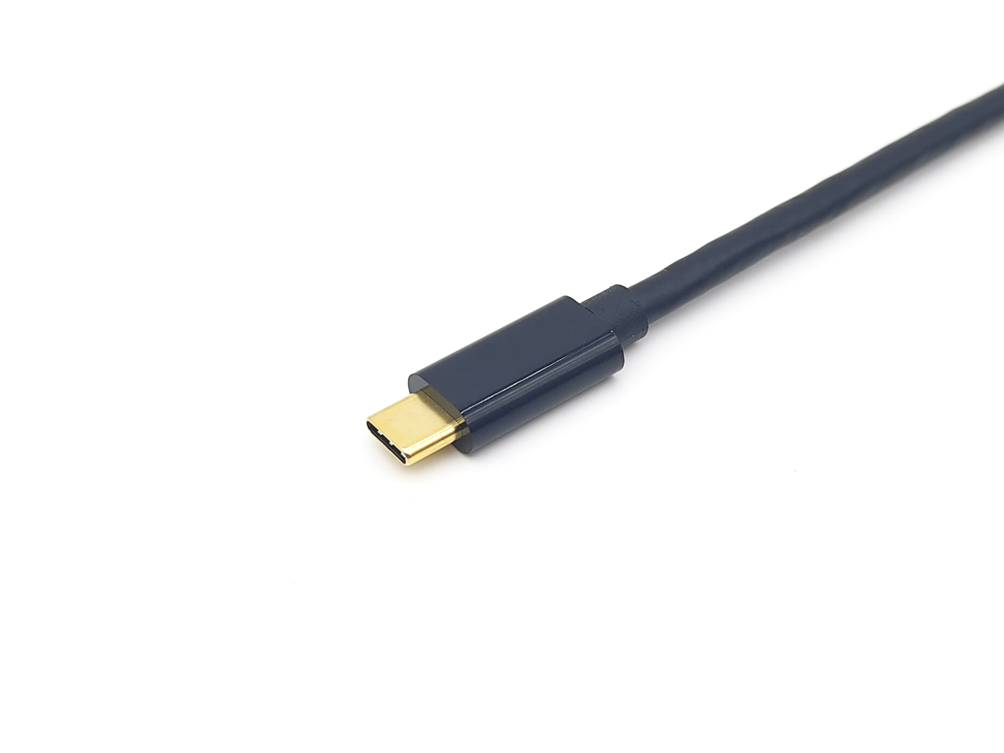 Se muestra un conector USB-C azul oscuro, en primer plano, sobre un fondo blanco. El conector es dorado.