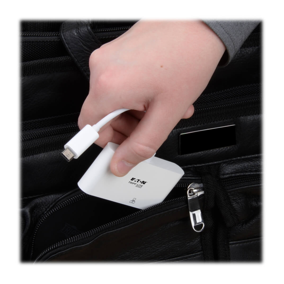 Ręka wyciąga biały adapter z czarnej torby. Adapter ma złącze USB-C.