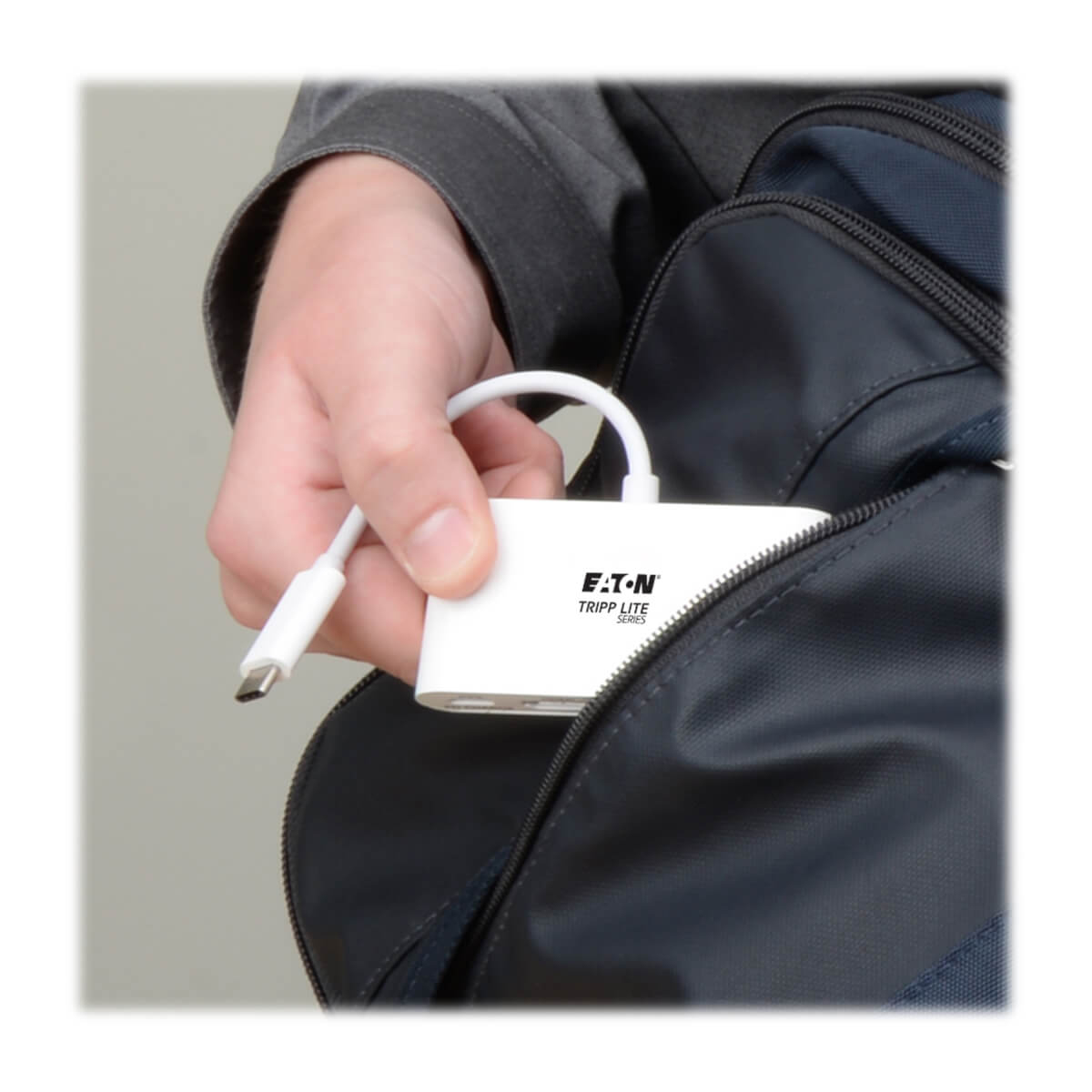 Ręka wyciąga białą przejściówkę z niebieskiej torby. Przejściówka ma złącze USB-C.