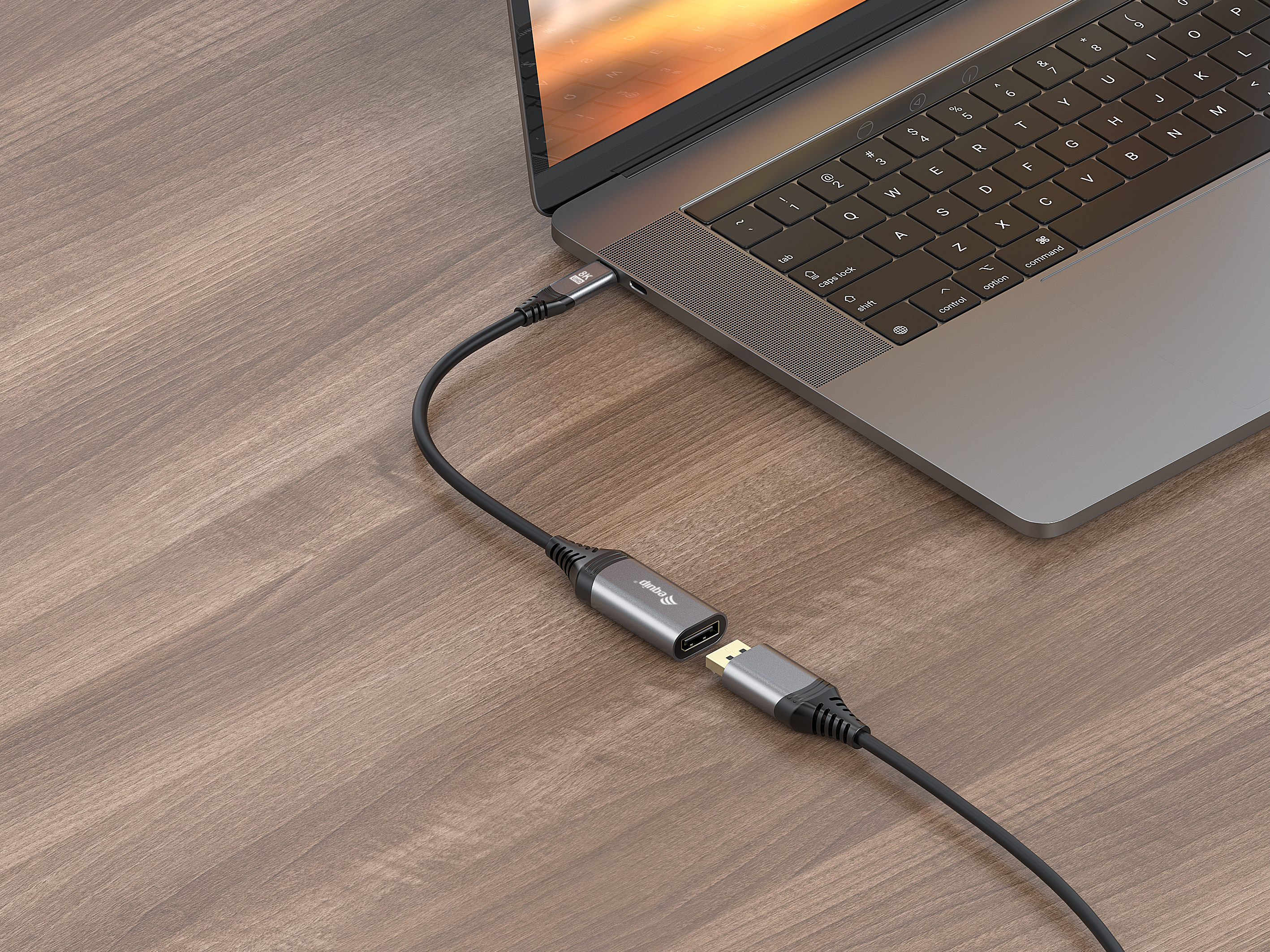 Adapter USB-C do DisplayPort podłączony do laptopa. Kabel jest czarny. Drewniane biurko.