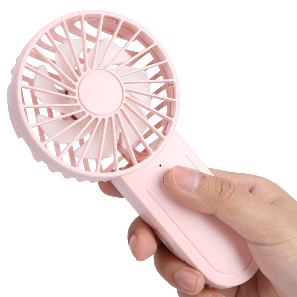 Ein rosa Handventilator, der von einer Hand gehalten wird. Der Lüfter ist eingeschaltet.