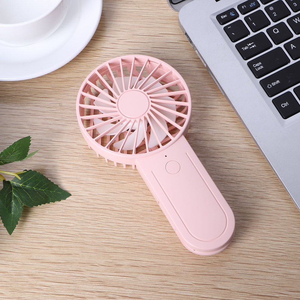 Rosa tragbarer Ventilator auf Holztisch. Laptop, Tasse und Teller in der Nähe.