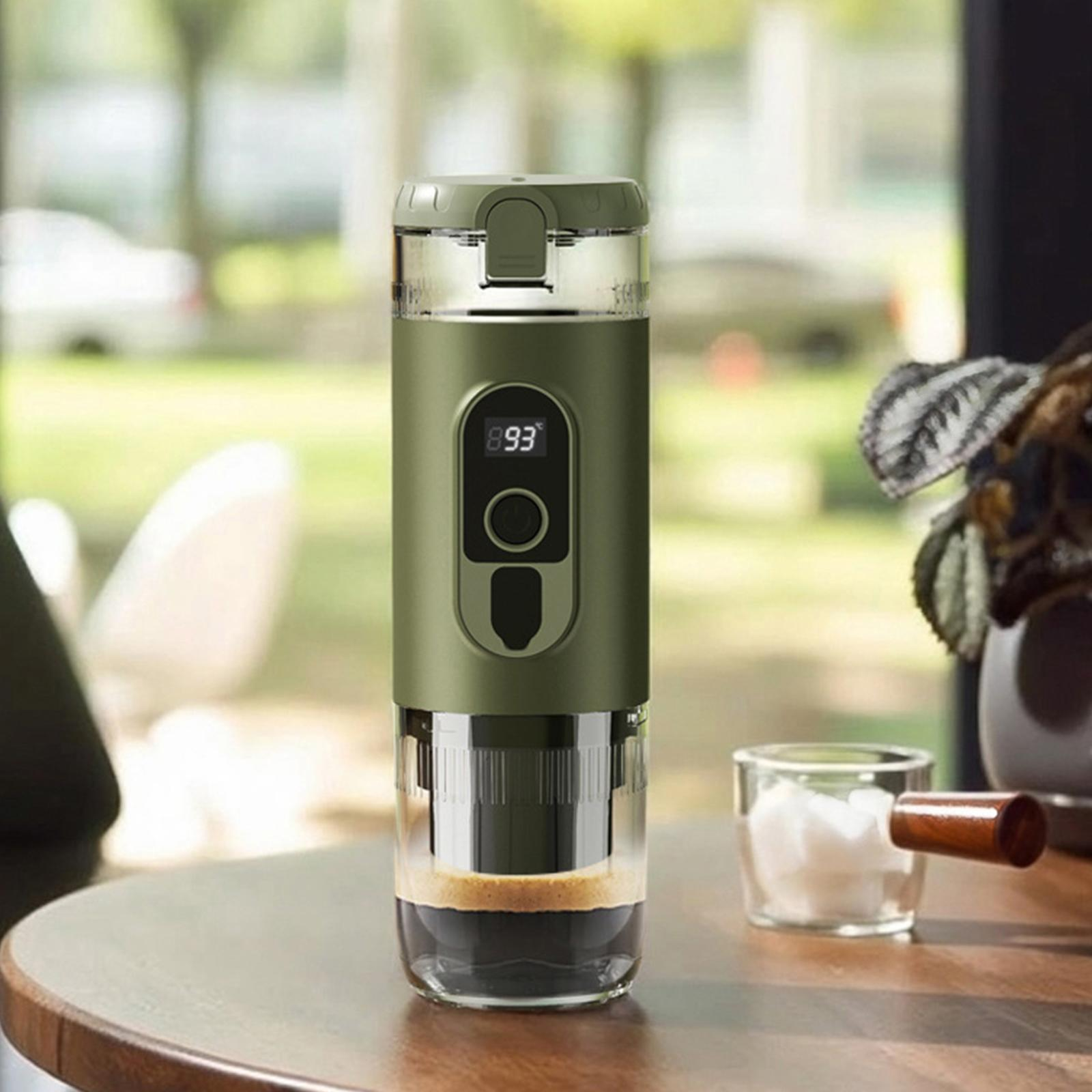 Tragbarer Kaffeezubereiter. Olivgrünes Gehäuse, Digitalanzeige und Glasbecher. Kaffee mit Schaum sichtbar.