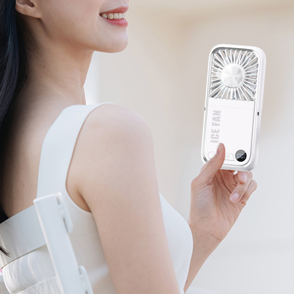 Eine Frau hält einen weißen tragbaren Ventilator. Der Ventilator zeigt 'ICE FAN' und einen kleinen digitalen Bildschirm.