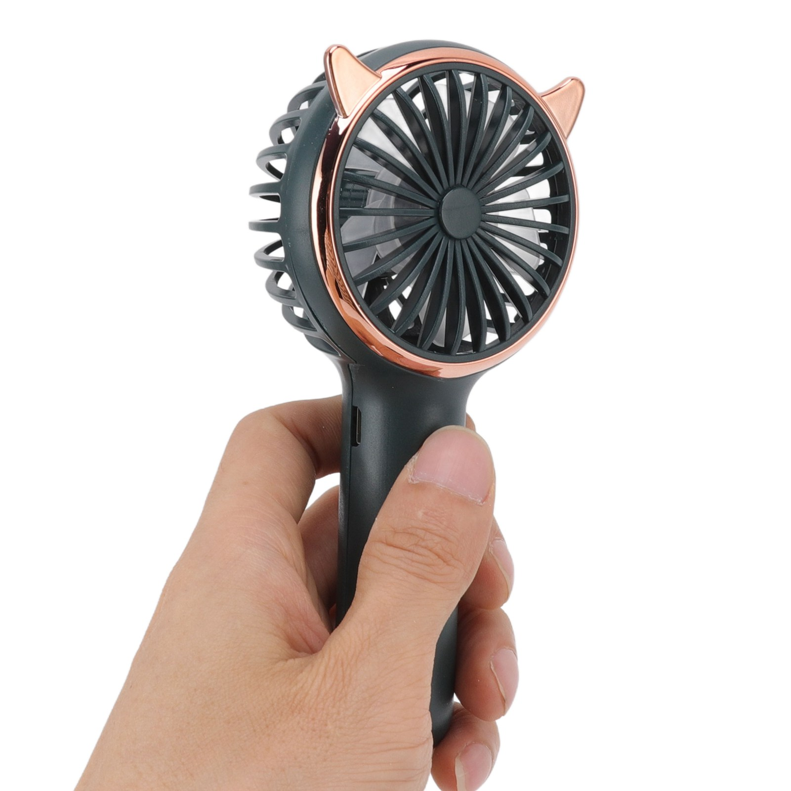 Eine Hand hält einen kleinen, tragbaren Ventilator mit schwarzem und goldenem Finish und einem Lüfterrad.
