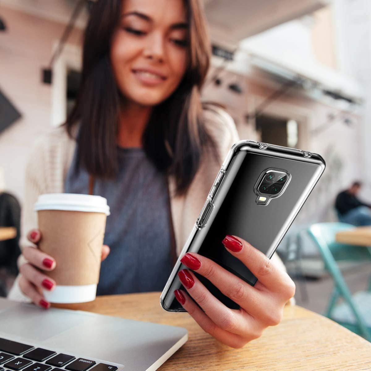 Mujer sosteniendo un teléfono. Hay una funda transparente en el teléfono. Taza de café en una mesa.
