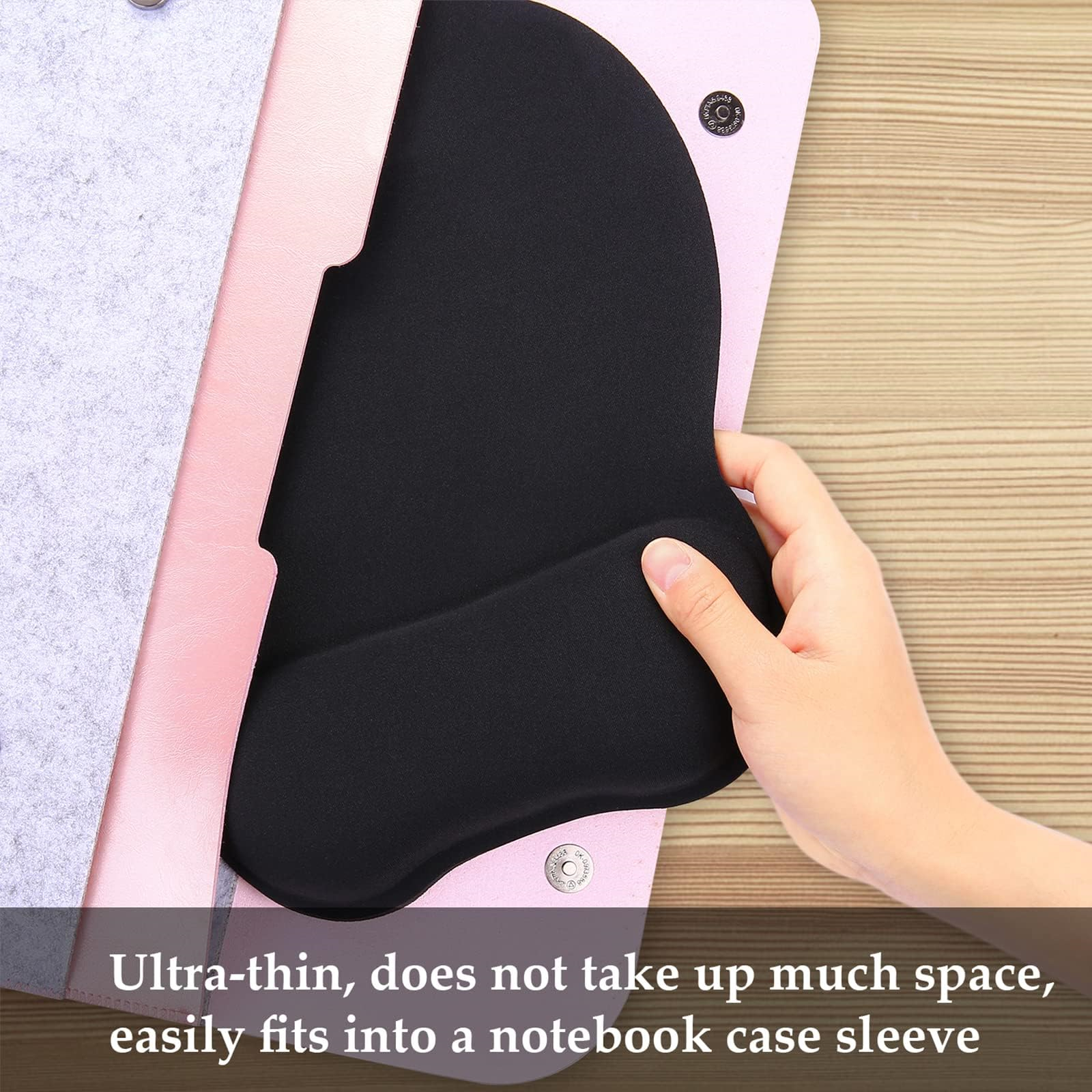 Hand legt ein schwarzes Mauspad in eine rosa Notebooktasche. Das Mauspad ist ergonomisch geformt.