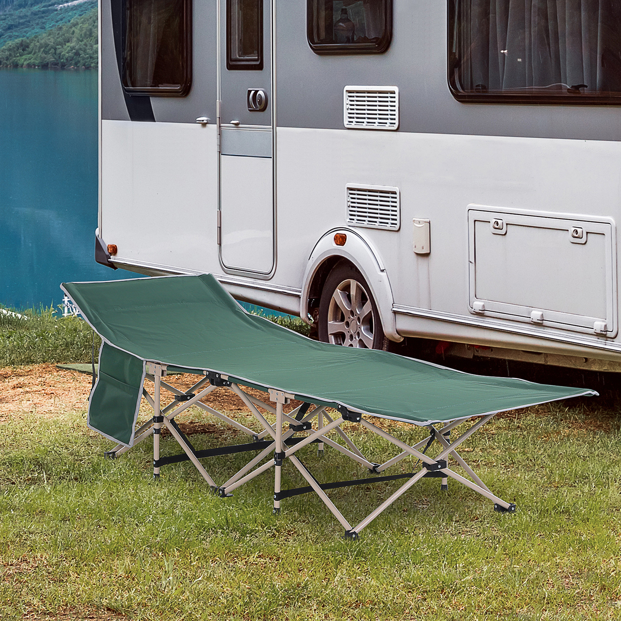 Grünes Campingbett auf Gras, in der Nähe eines Wohnmobils. Der Hintergrund enthält einen See.