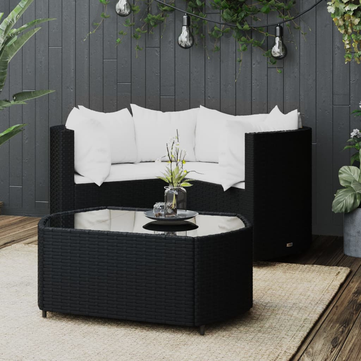 Ein schwarzes Sitzmöbel-Set für draußen mit weißen Kissen und einem Tisch mit Glasplatte auf einer Holzterrasse.