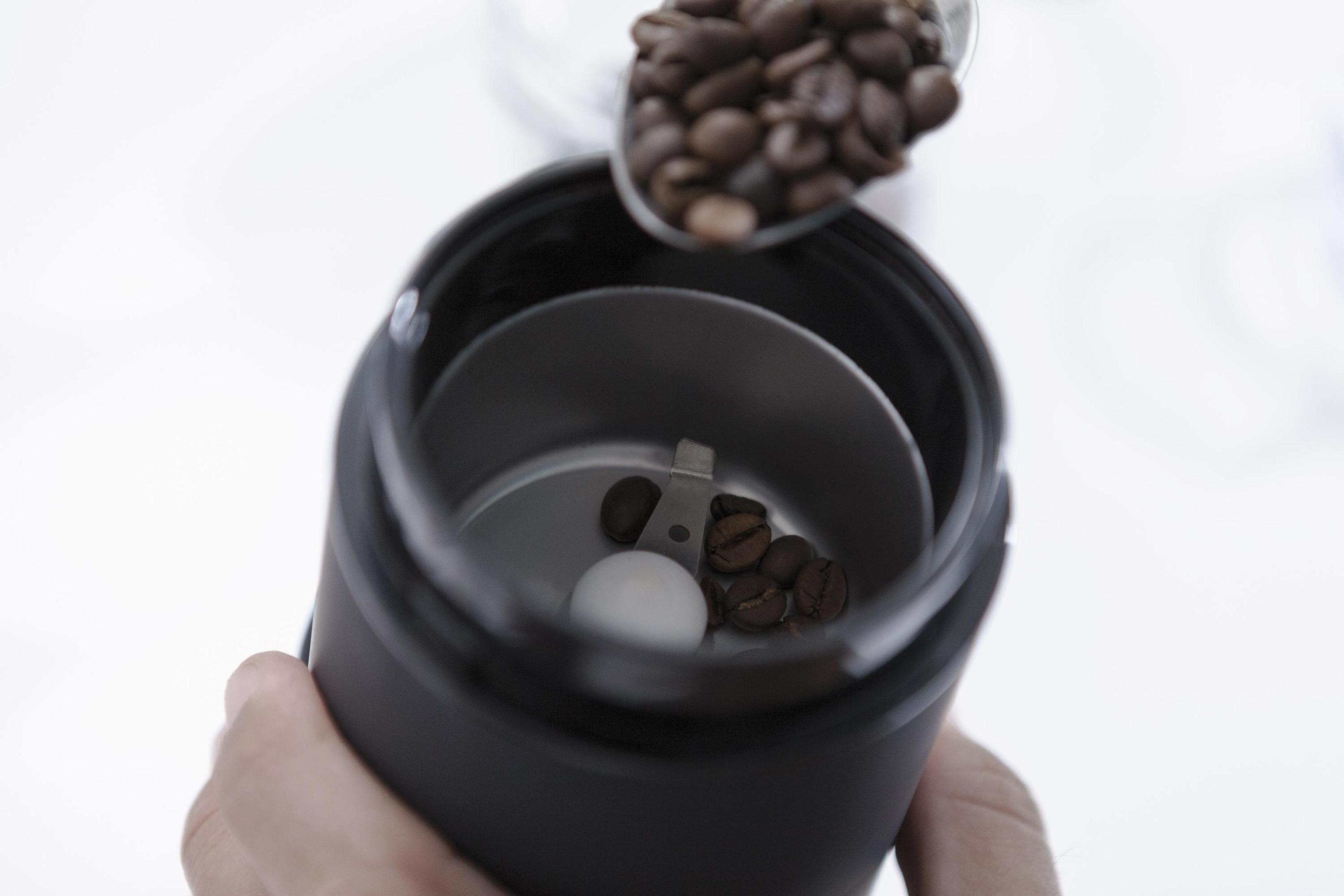 Ziarna kawy wlewane do młynka do kawy.