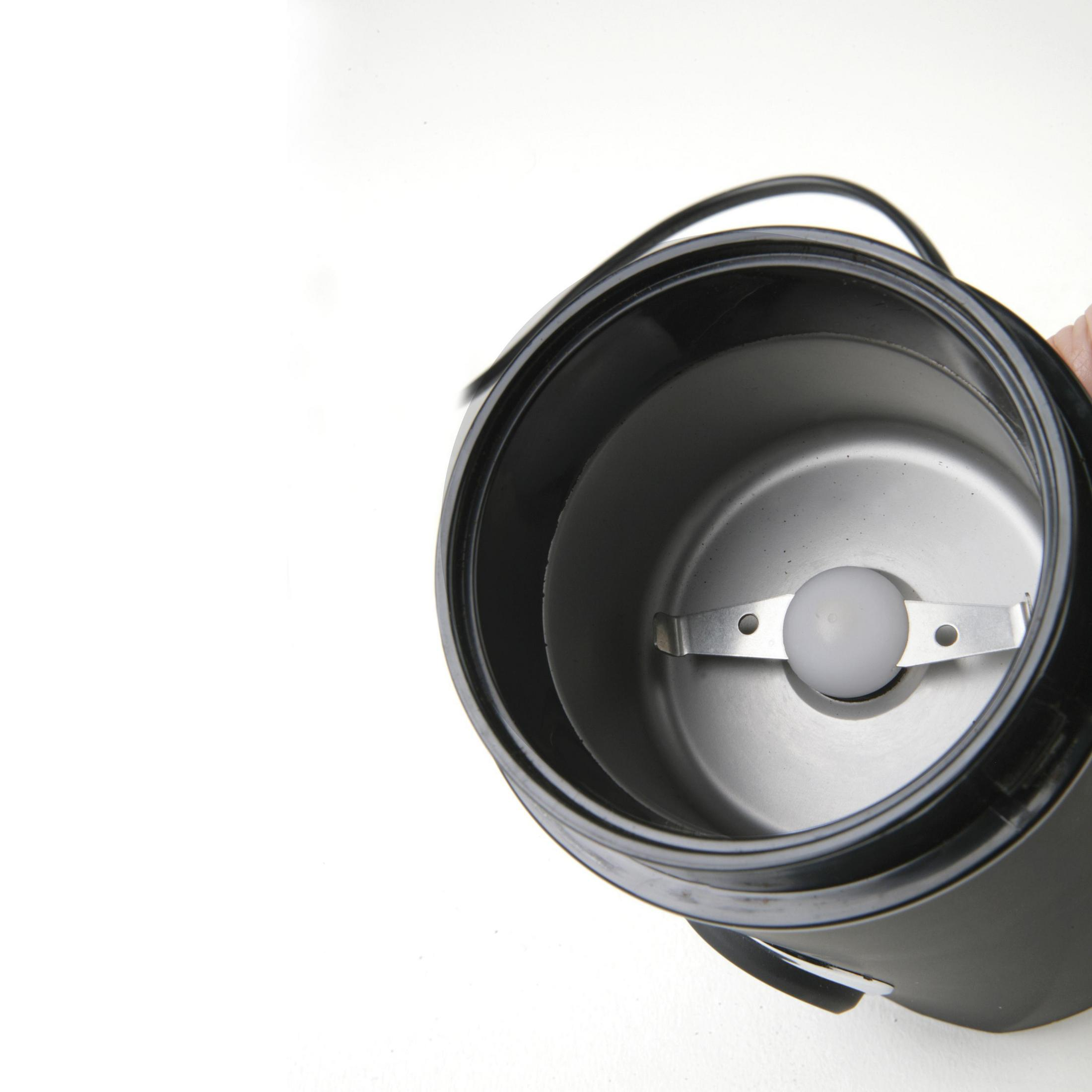 Wnętrze młynka do kawy z ostrzem i czarnym pojemnikiem.