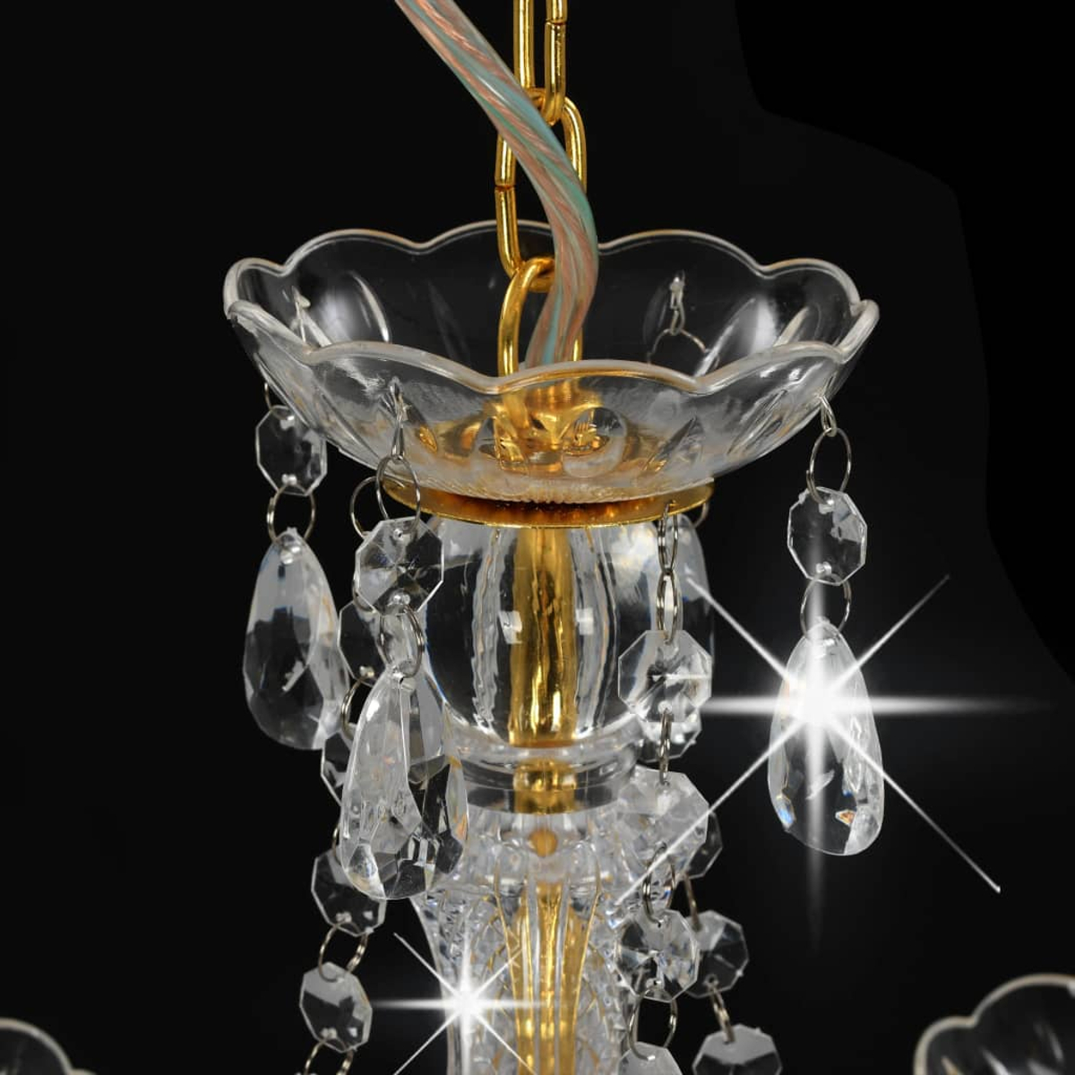 Nahaufnahme eines Kronleuchters mit Kristallanhängern und goldenen Akzenten. Schwarzer Hintergrund.