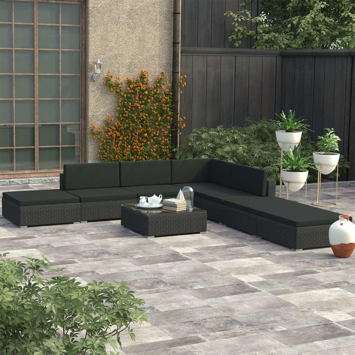 Terrassenmöbel-Set für den Außenbereich mit schwarzen Kissen und Tisch.
