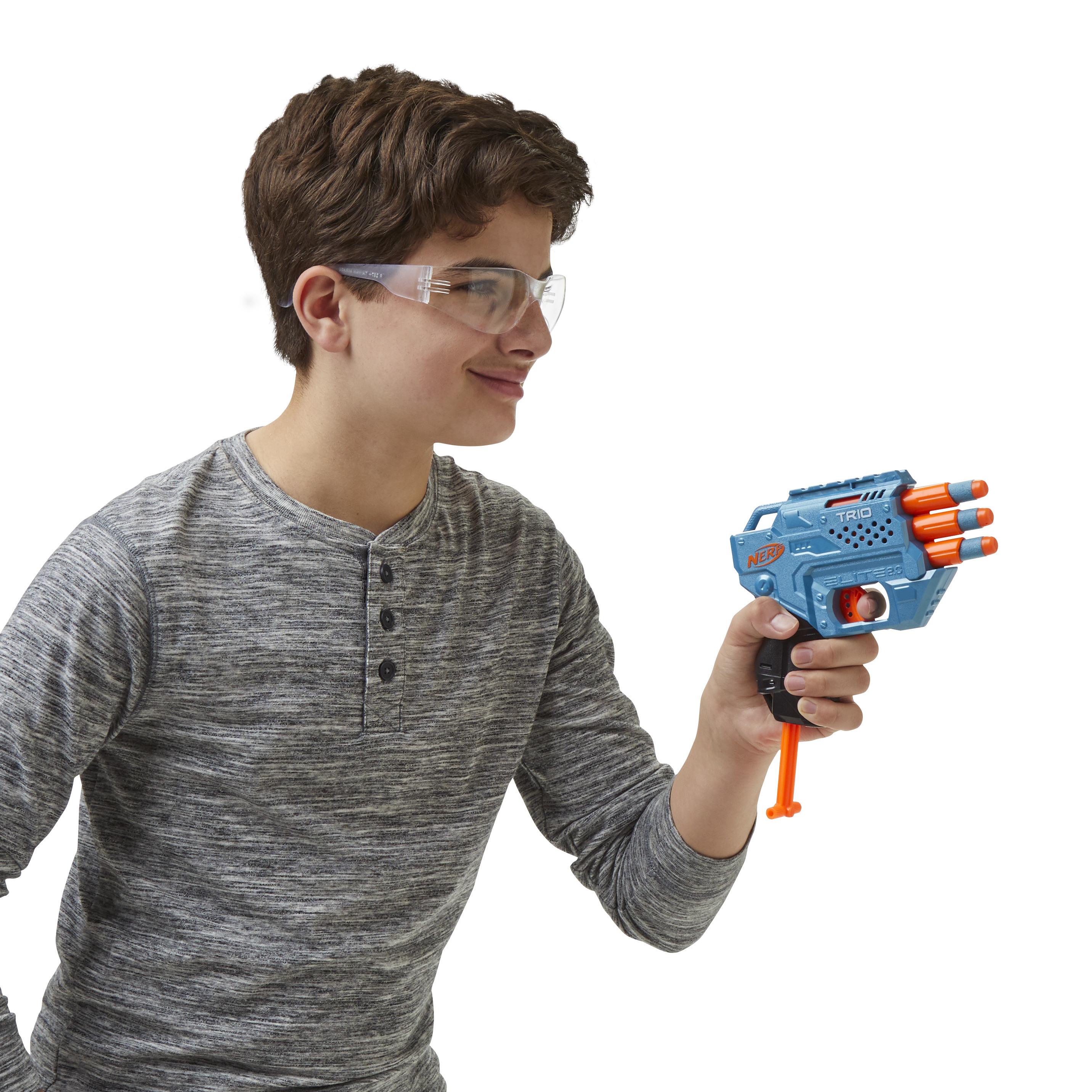 Ragazzo adolescente con occhiali protettivi, che guarda a destra, tiene in mano una pistola Nerf blu con dardi arancioni.