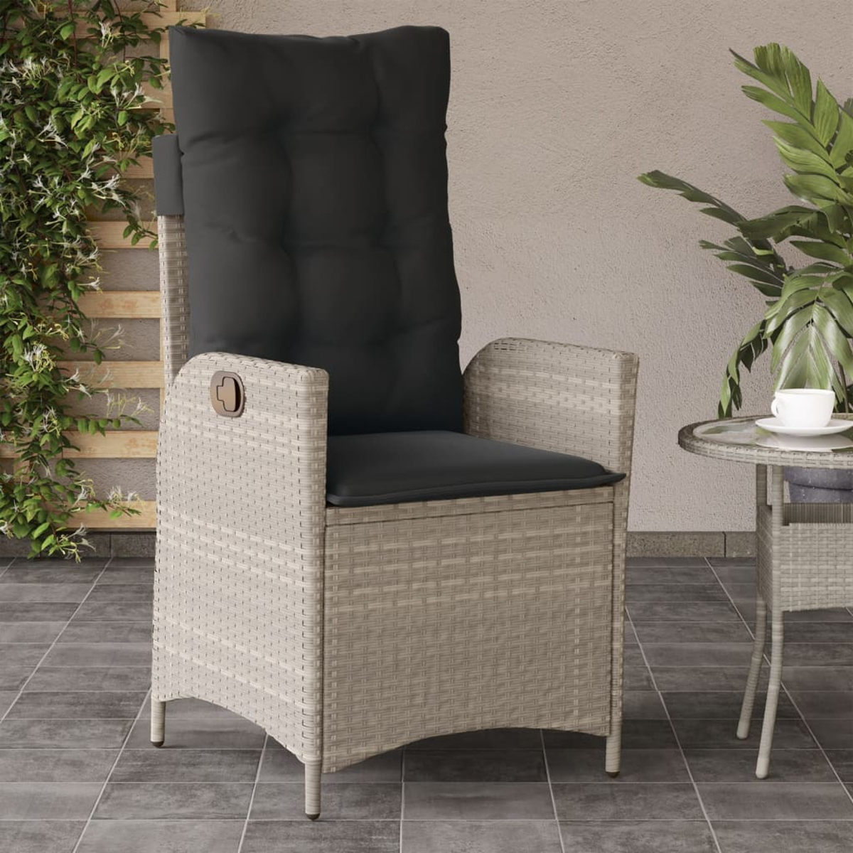Una sedia in vimini beige con un cuscino nero. Un tavolino con una tazza sullo sfondo.