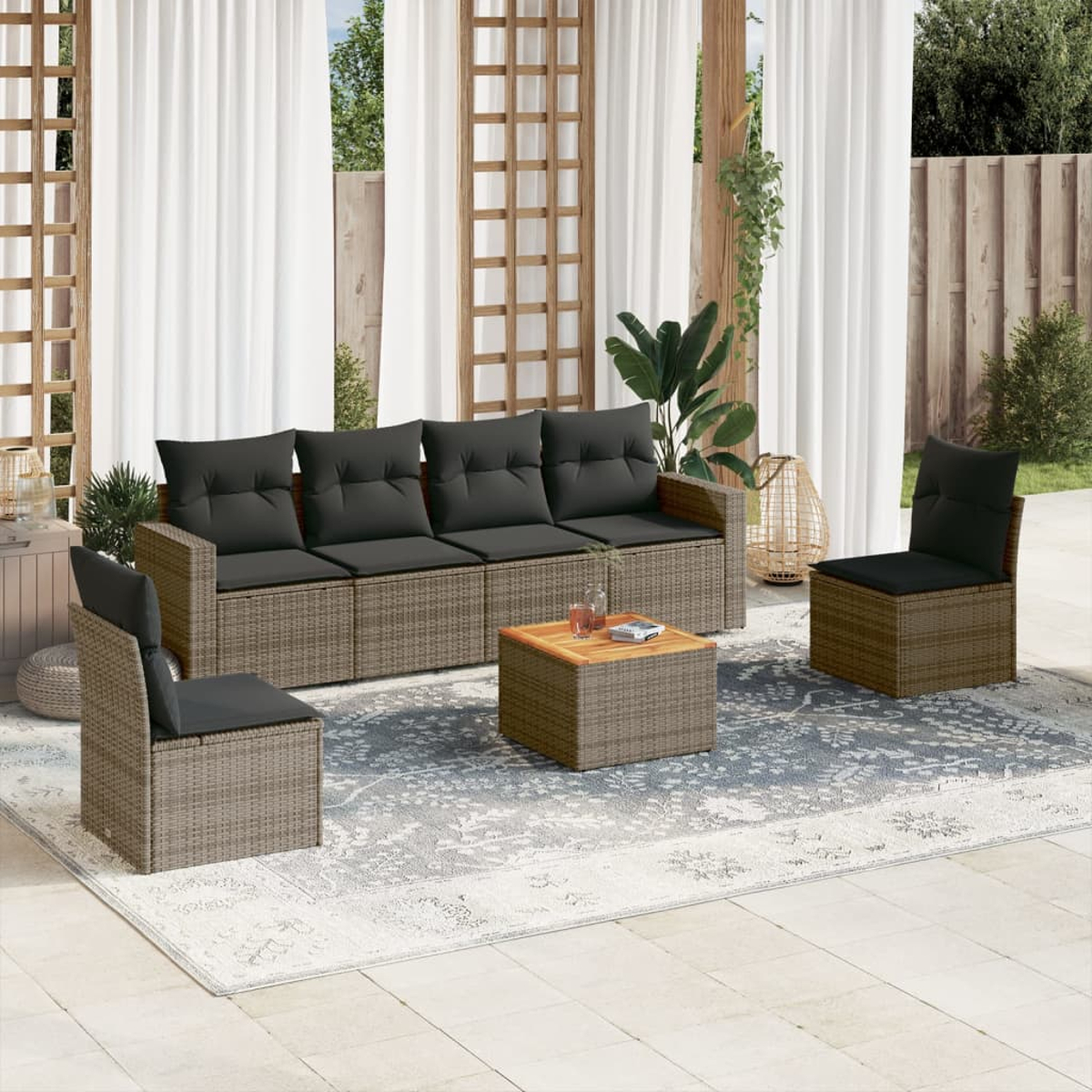 Outdoor-Rattan-Möbelset mit Sofa, zwei Stühlen und einem Tisch auf einem gemusterten Teppich.