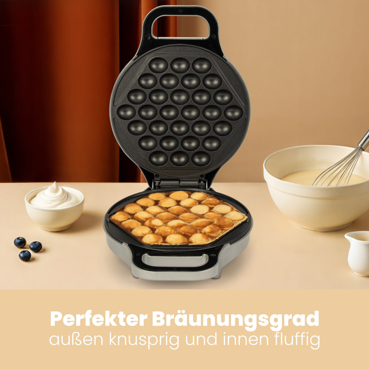 Gofrownica z upieczonymi goframi. Biała miska z bitą śmietaną, jagodami i ciastem.