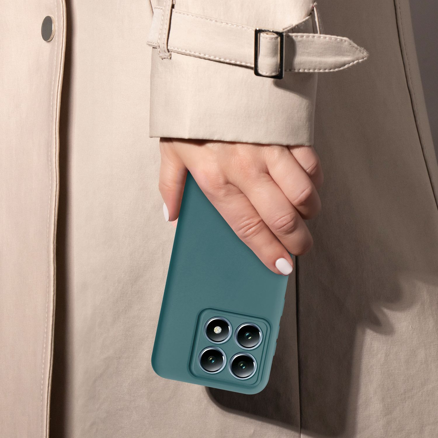 Hand hält eine türkis Handyhülle vor einem beigen Trenchcoat.