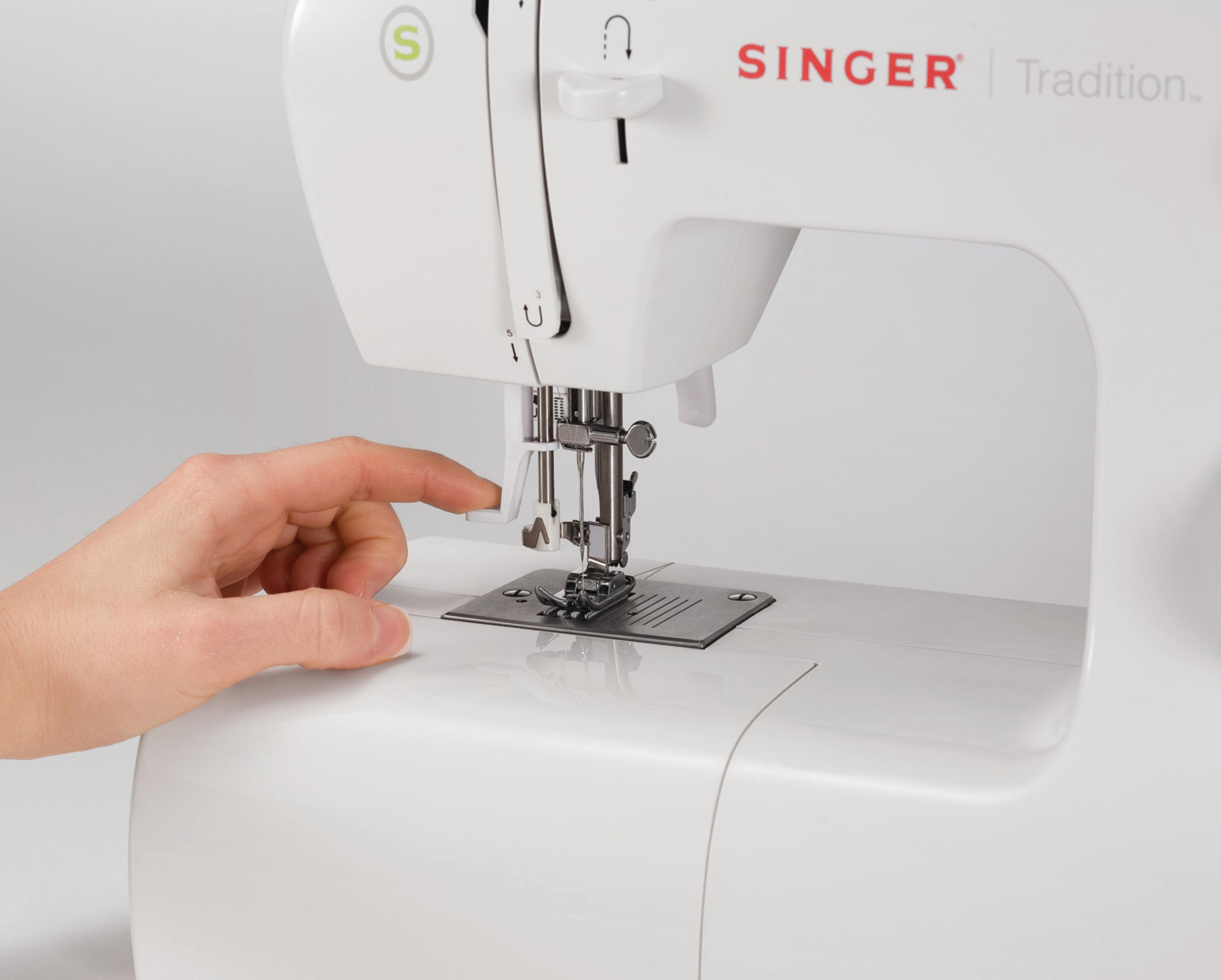 Zbliżenie białej maszyny do szycia Singer, z dłonią dotykającą obszaru igły.