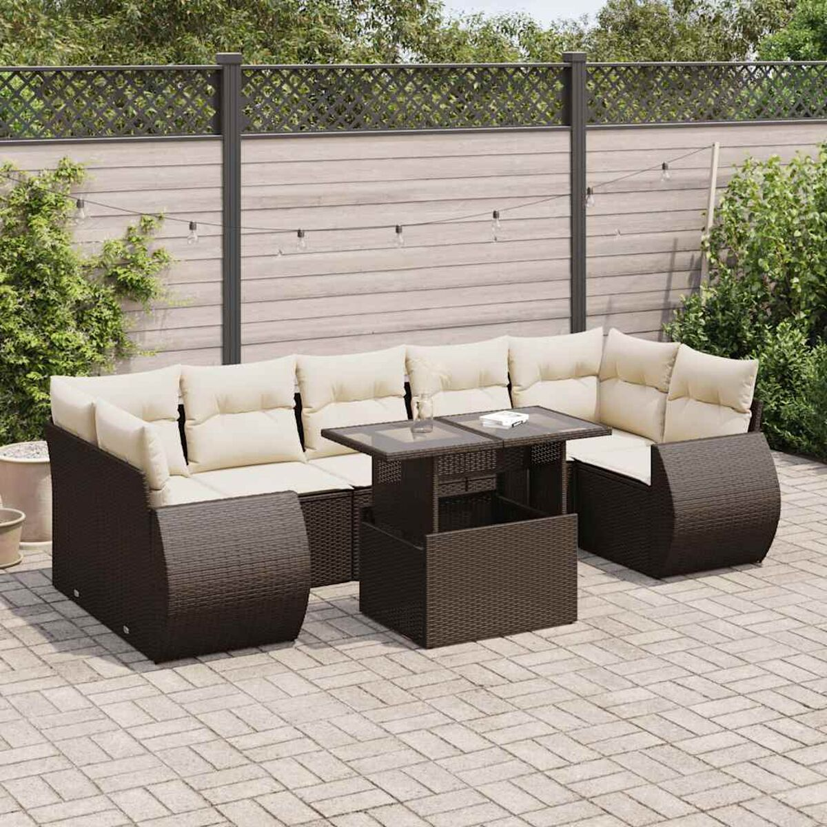 Ein Outdoor-Terrassenmöbel-Set, braunes Korbgeflecht mit cremefarbenen Kissen, auf einer Backsteinterrasse.