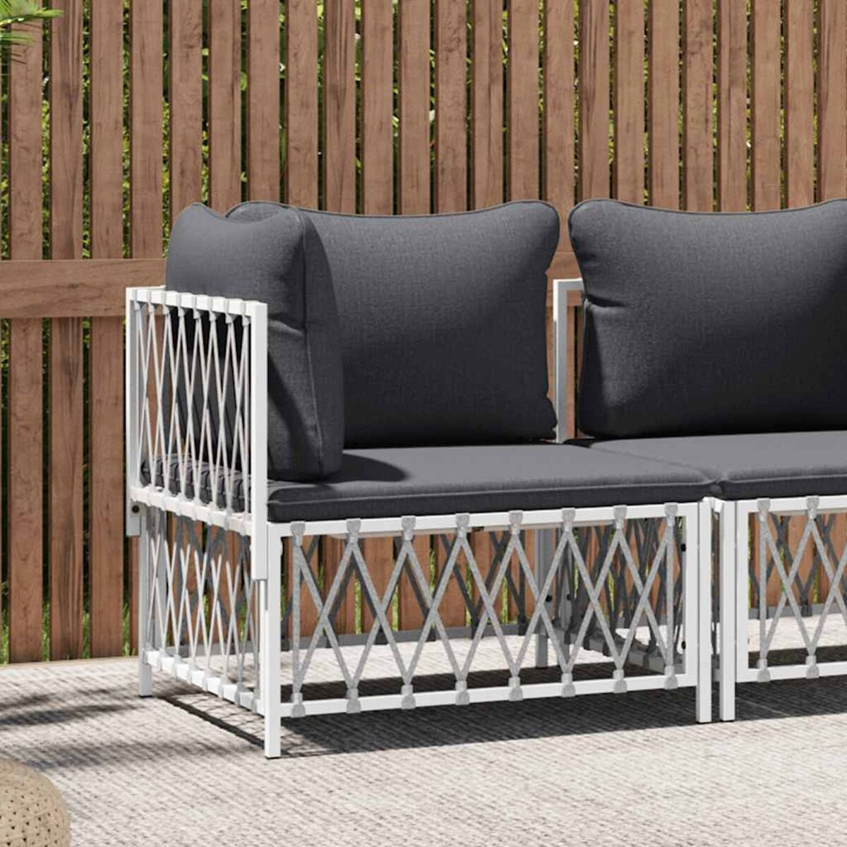 Weißes Sitzmöbel-Set für draußen mit dunkelgrauen Kissen auf einer Terrasse.