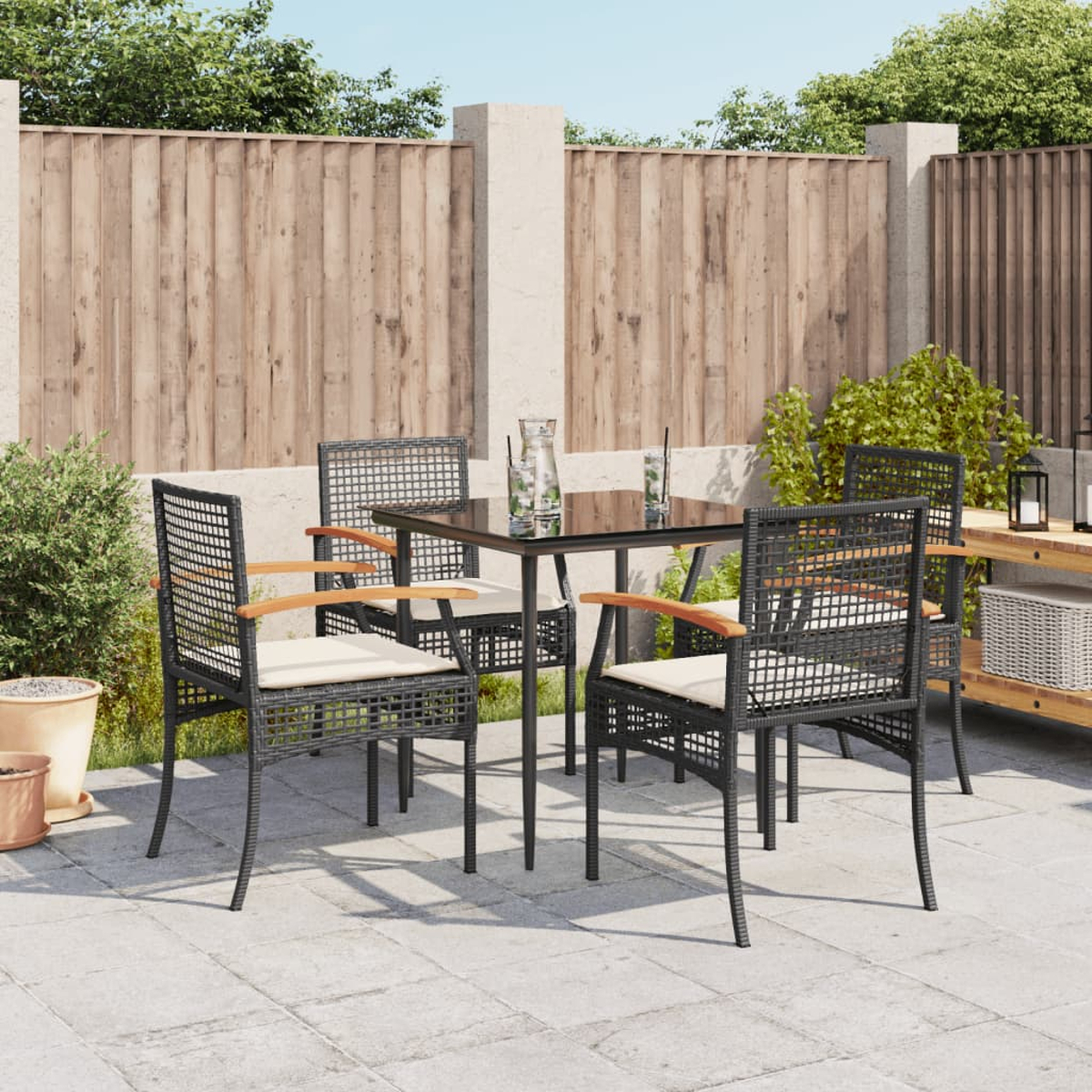 Terrassenset: schwarze Stühle und Tisch mit Holzarmlehnen in einem Garten.