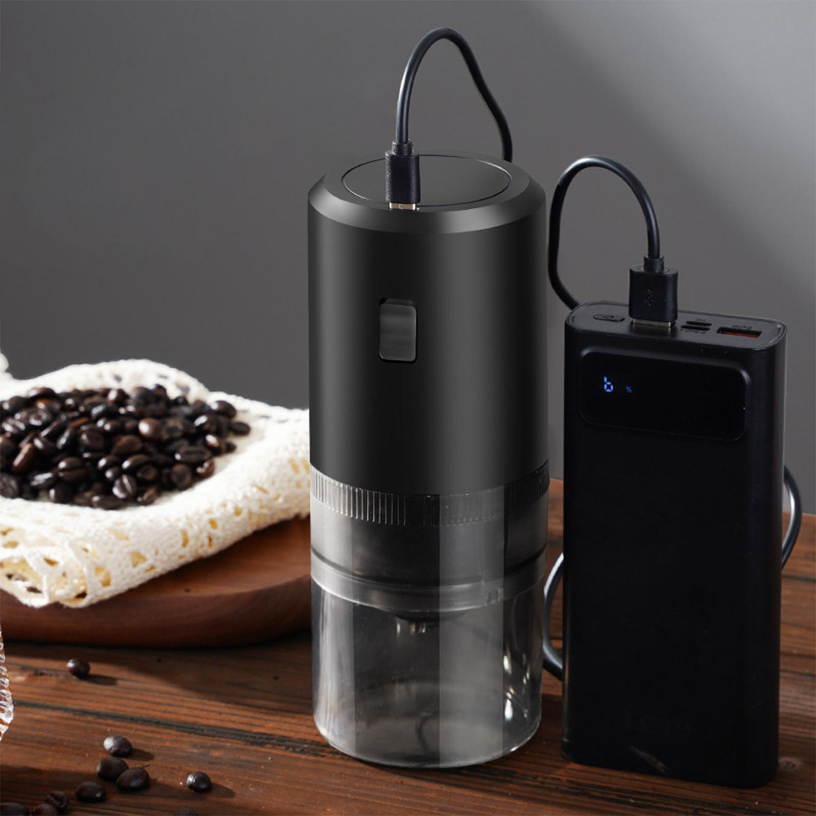 Schwarze Kaffeemühle mit Powerbank über USB verbunden. Kaffeebohnen auf Holzoberfläche.
