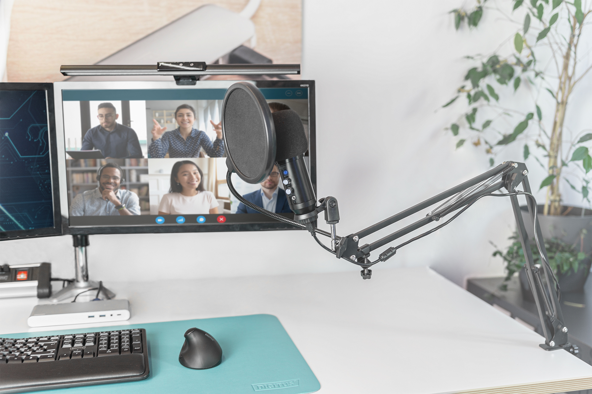 Un'impostazione di home office con microfono, doppi monitor e una videochiamata in corso.