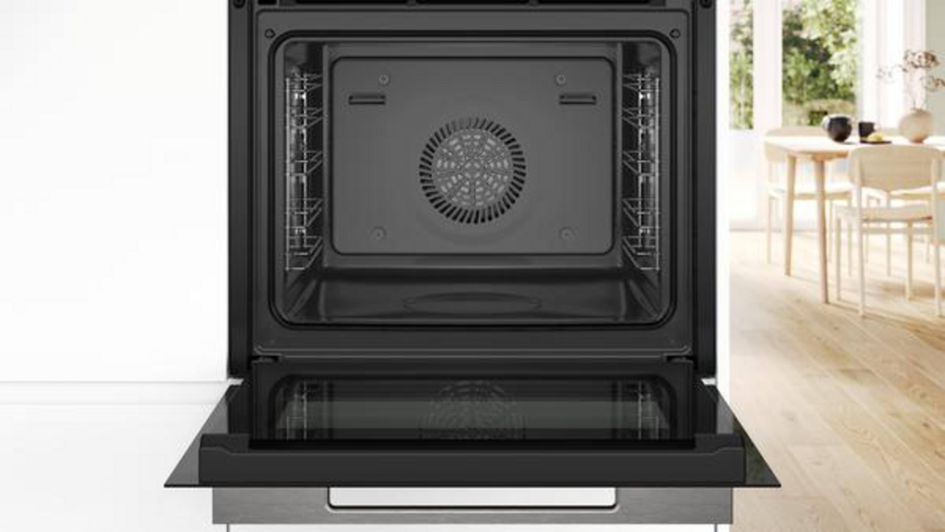 Intérieur de four noir ouvert avec ventilateur et grilles, sur fond blanc.