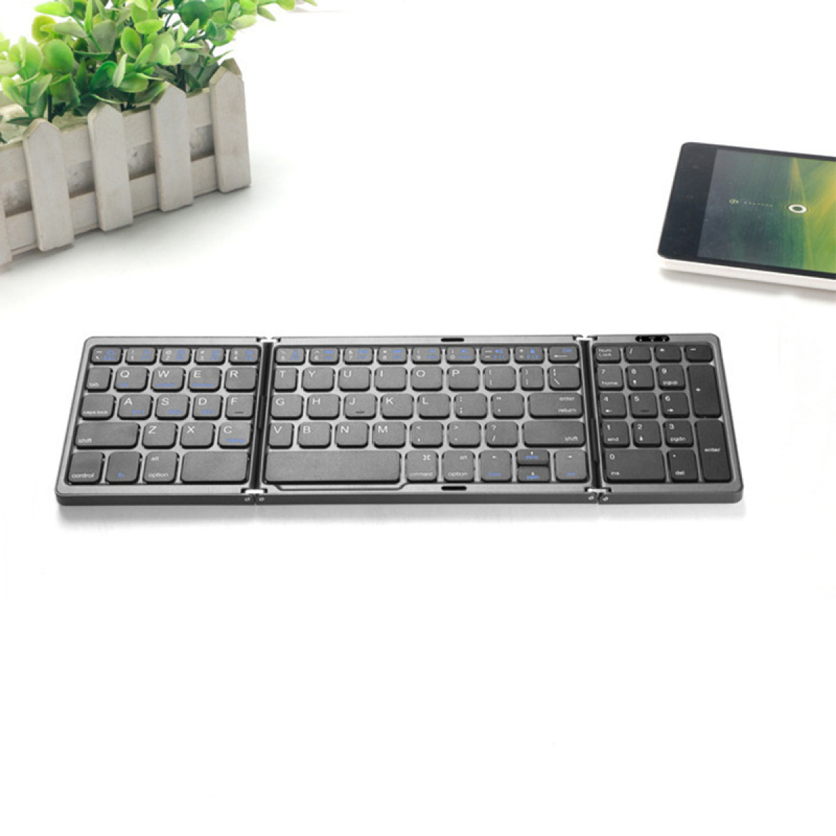 Eine Tastatur auf einem Tisch. Ein Tablet befindet sich oben rechts.