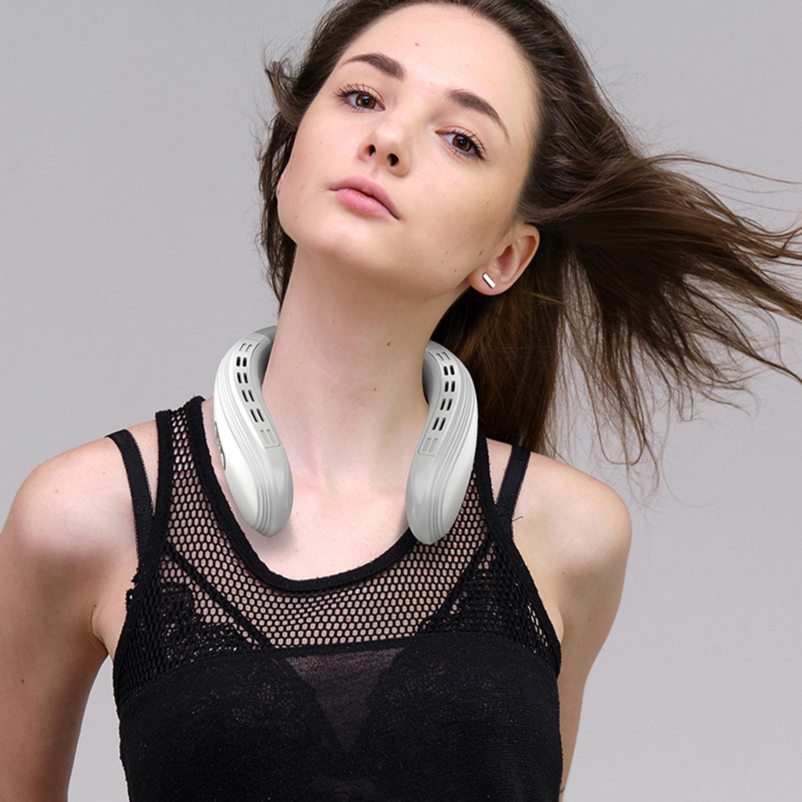 Eine Frau mit einem weißen Nackenventilator. Sie schaut neutral in die Kamera. Schwarzes Top.