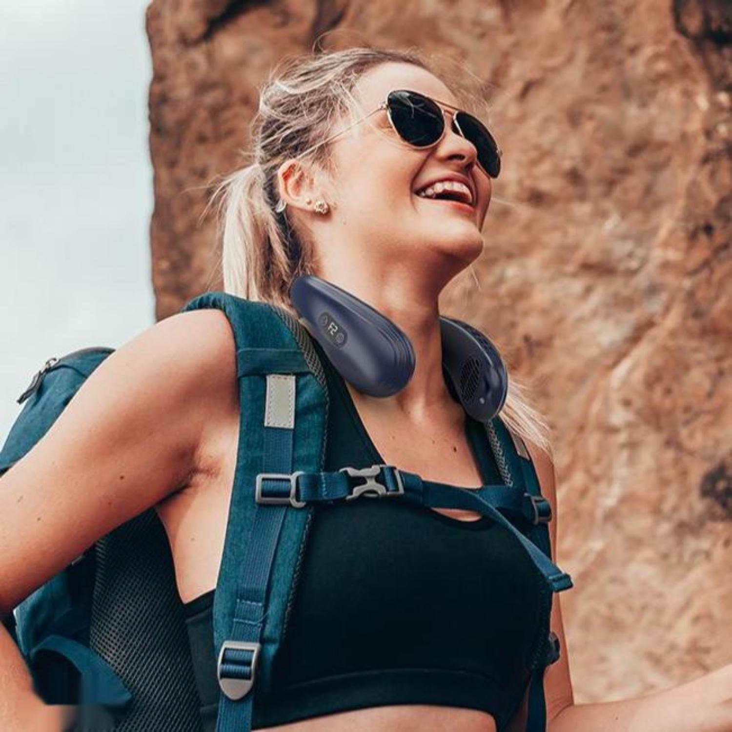 Frau mit Sonnenbrille und Nackenfächer lächelt, trägt Rucksack, im Freien.