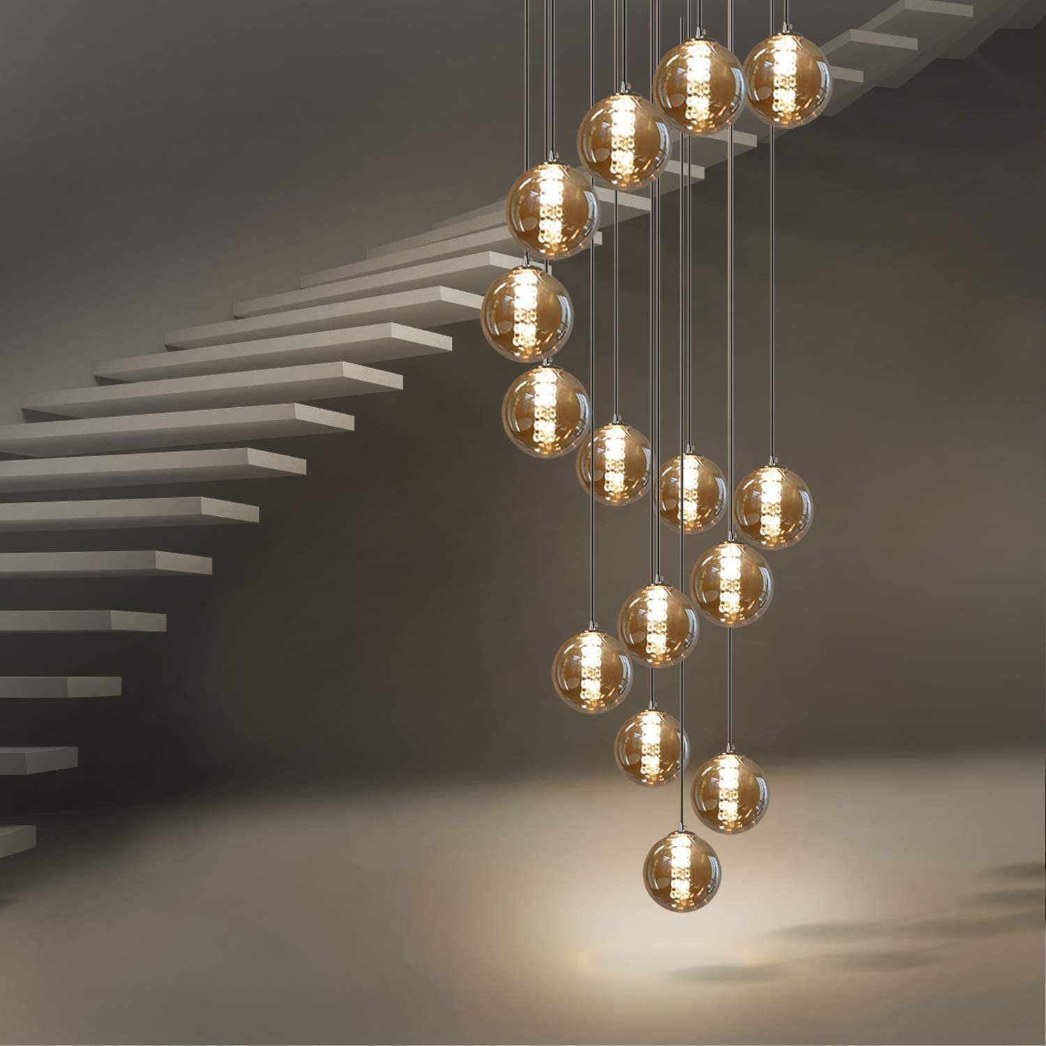Eine Spirale aus Hängelampen mit runden, bernsteinfarbenen Glaskugeln. Die Lichter gehen in der Nähe einer Treppe herab.