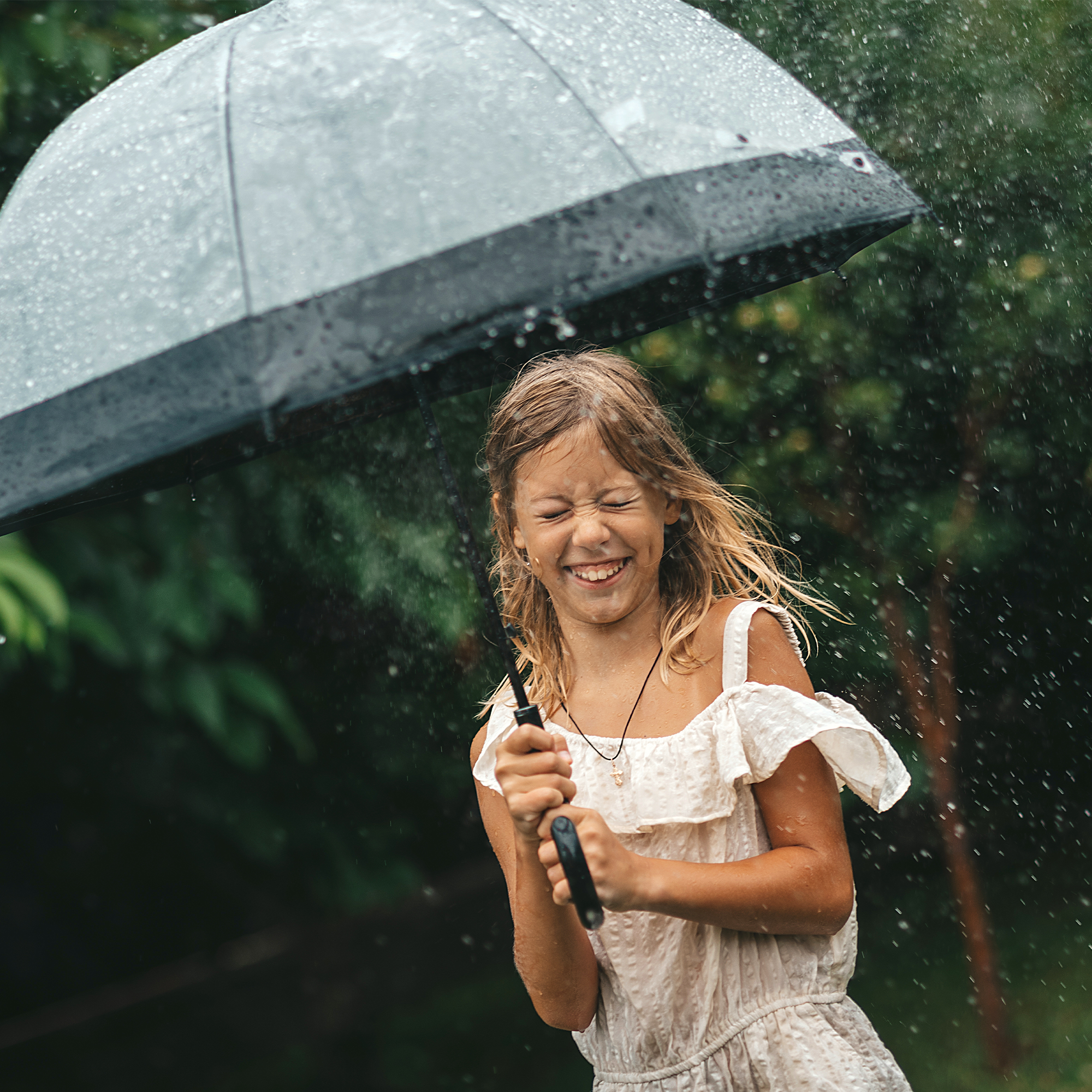 Une fille sourit sous un parapluie sous la pluie.