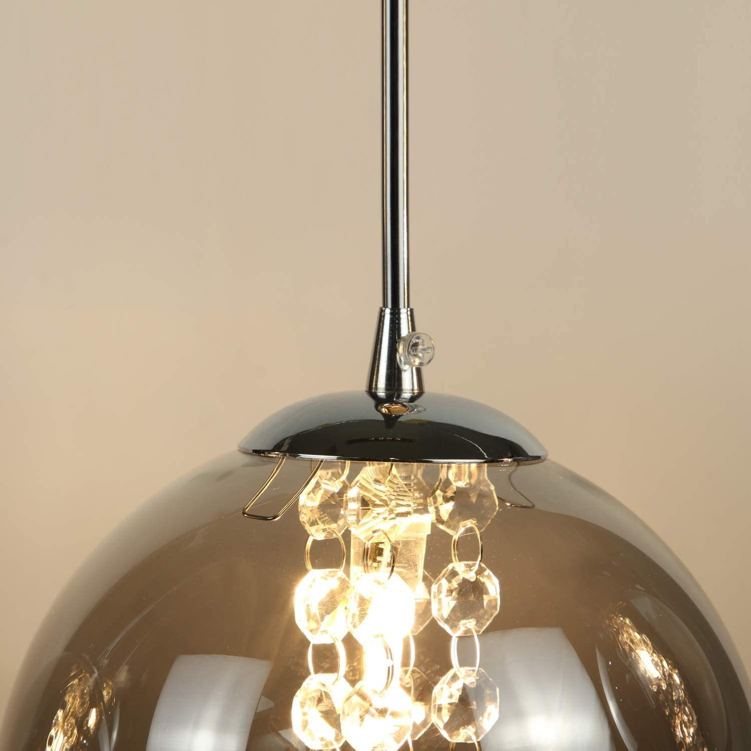 Lampa wisząca z szklanym kloszem i ozdobnymi kryształami. Światło świeci.
