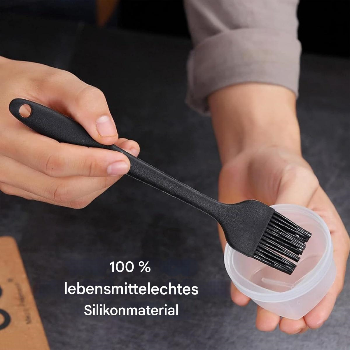 Eine Hand hält einen schwarzen Backpinsel über einem weißen Behälter.