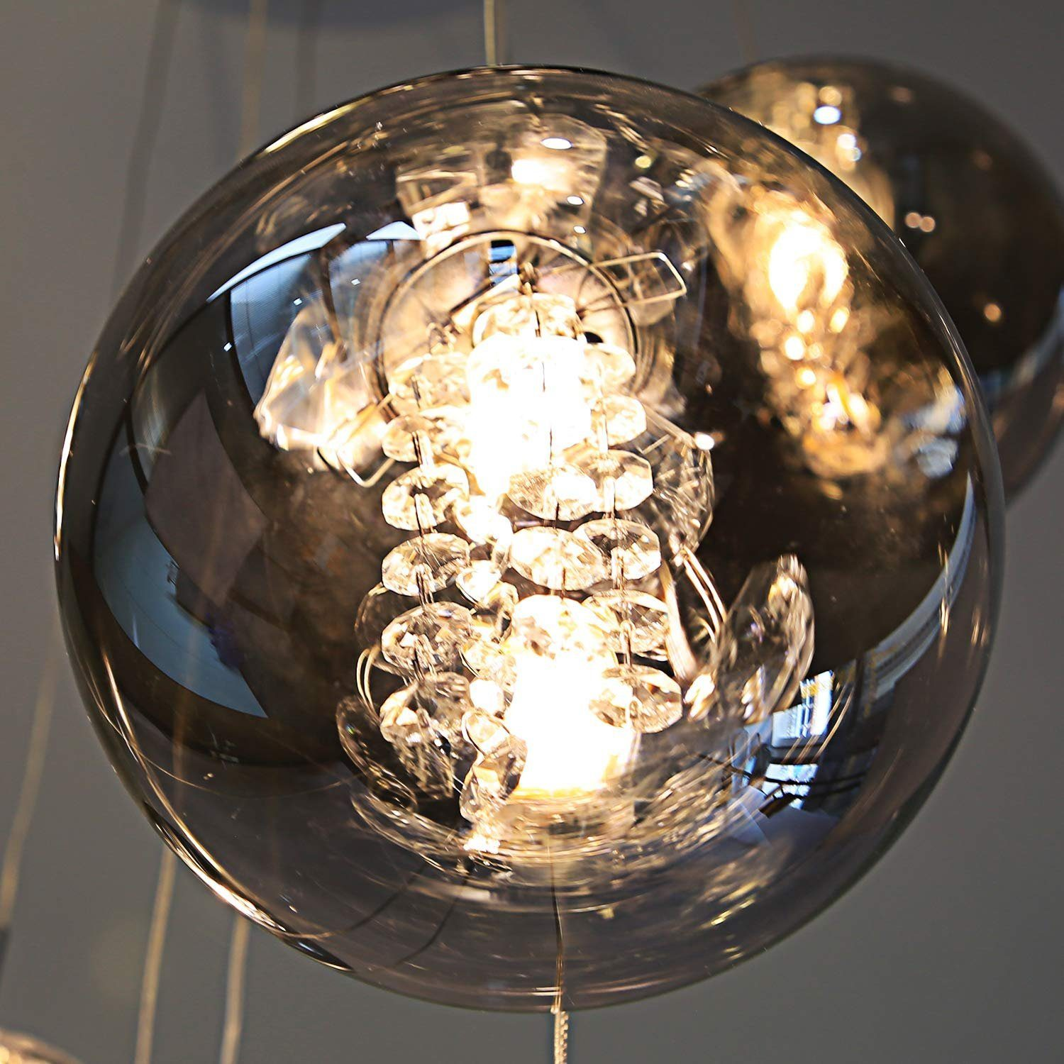 Nahaufnahme eines Glasleuchters mit hängenden Kristallakzenten und einer hellen Lichtquelle.