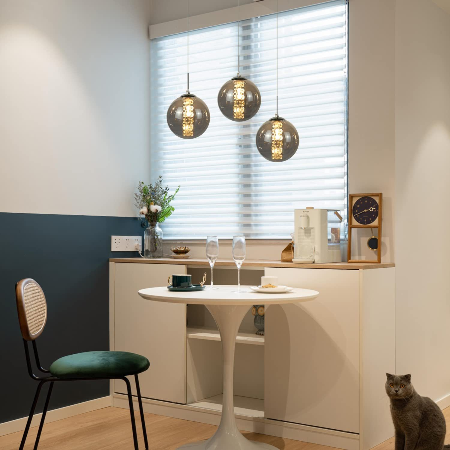 Moderne Küche mit Kugelleuchten, Tisch, Stuhl und Katze. Der Stil ist elegant.