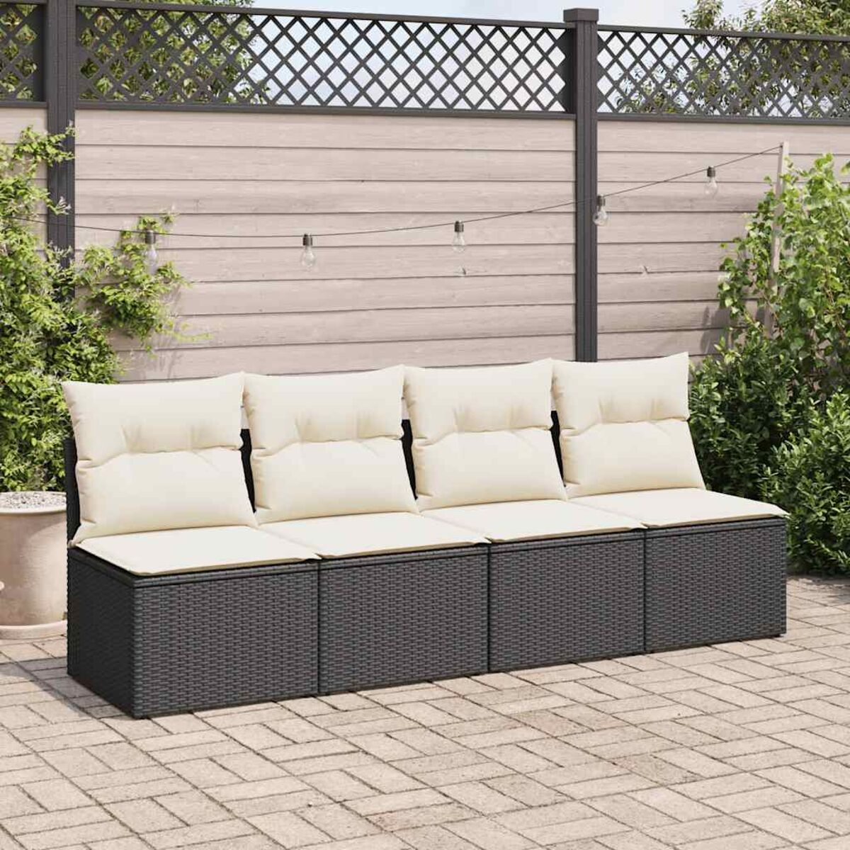 Arredamento esterno: un divano in vimini grigio scuro con cuscini color crema. Una recinzione in legno sullo sfondo.